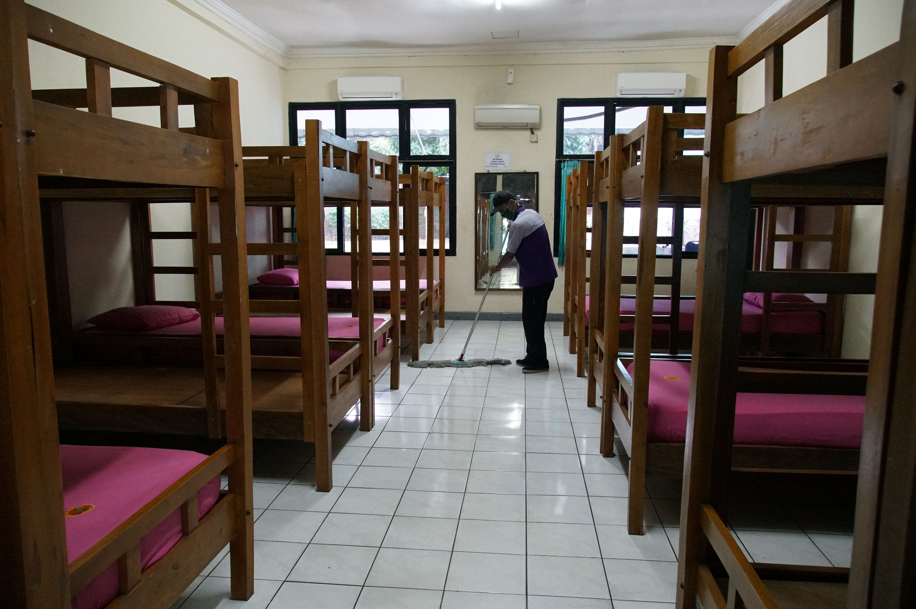 Petugas membersihkan lantai kamar yang akan digunakan sebagai tempat isolasi mandiri di Graha Wisma TMII