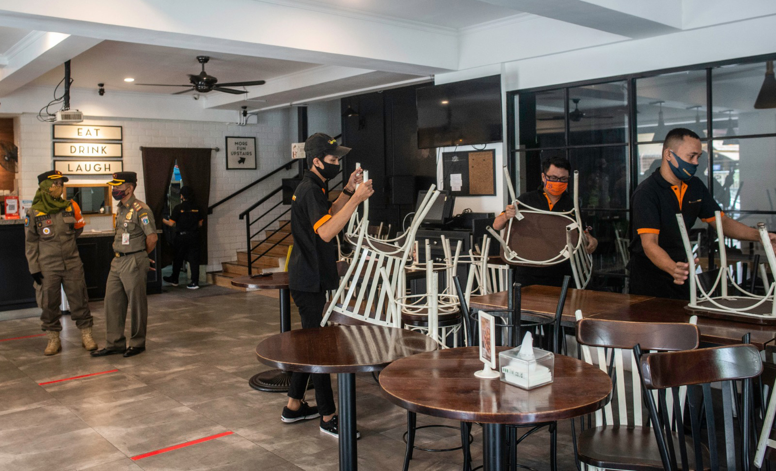  Karyawan restoran mengangkat kursi dan meja saat terjaring razia PSBB Jakarta di kawasan Sunter Agung, Jakarta