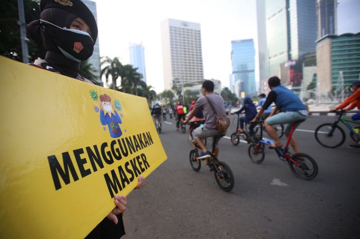 Polisi melakukan kampanye sosialisasi menggunakan masker dan cuci tangan pada PSBB Transisi  di Bundaran HI Jakarta.