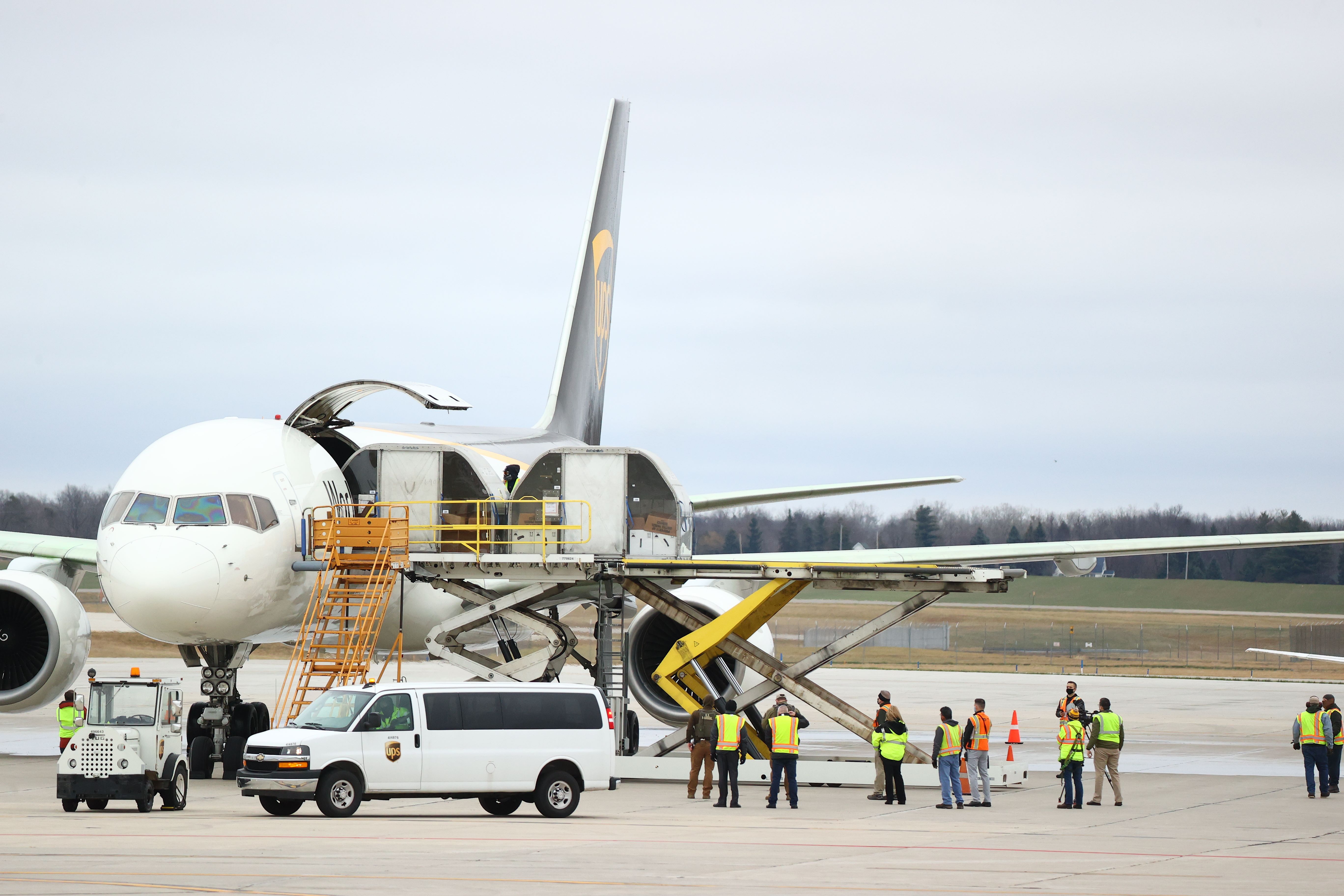 Pekerja memasukkan vaksin covid-19 produksi Pfizer dan BioNTech ke pesawat milik UPS di bandara di Lansing, Michigan, AS.