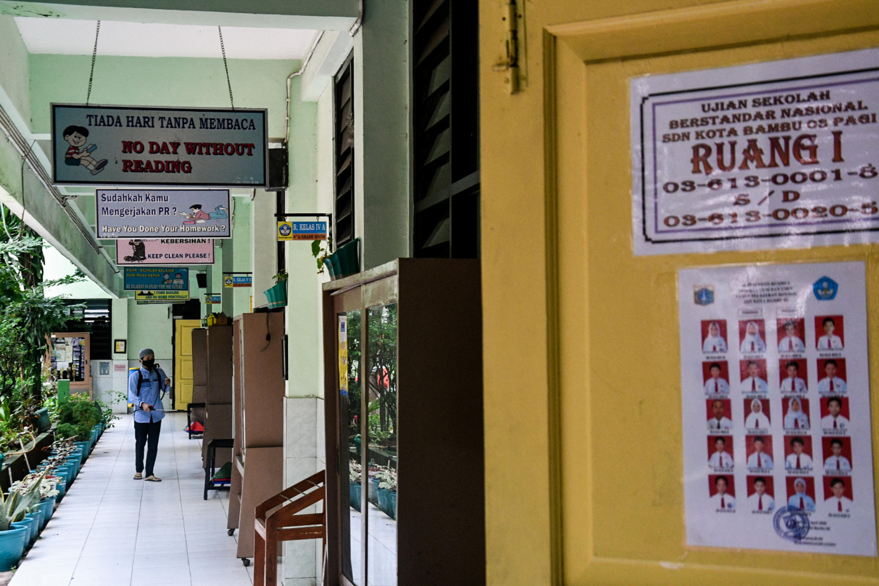 Ilustrasi petugas menyemprotkan cairan disienfektan di sekolah wilayah Jakarta.