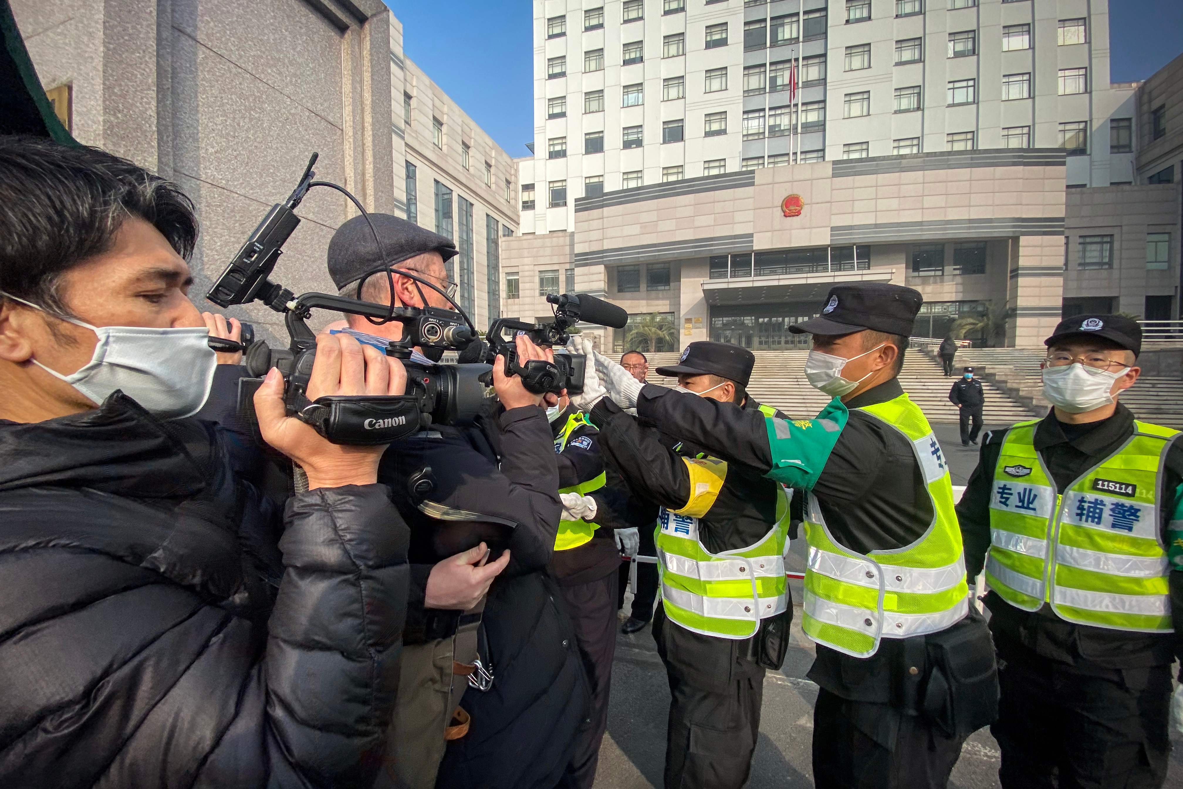 Polisi berusaha melarang jurnalis mengambil gambar sidang terhadap citizen journalist, Zhang Zhan yang melaporkan terkait pandemi covid-19 