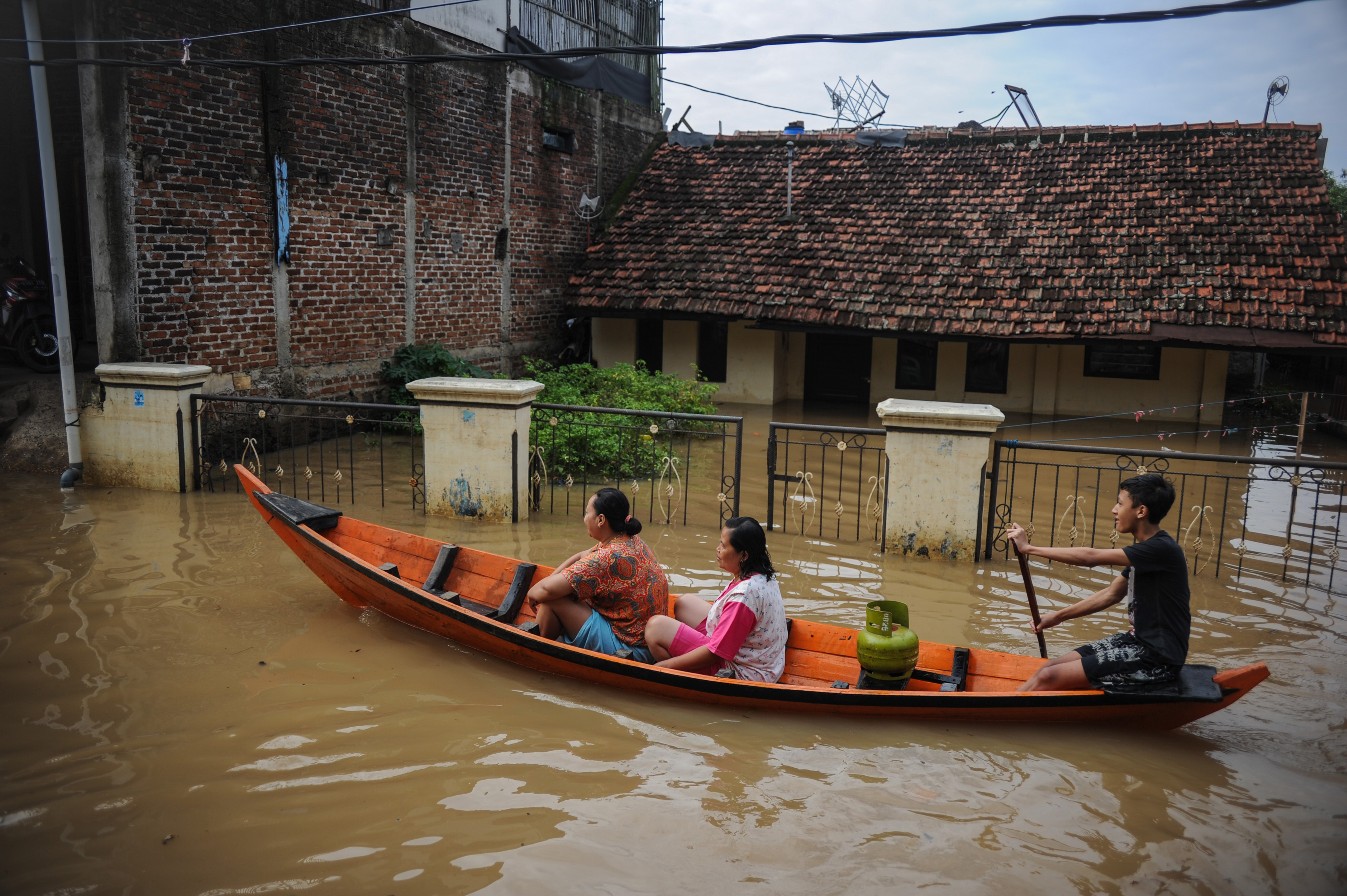 Warga menggunakan perahu melintasi banjir yang melanda Bojongasih, Dayeuhkolot, Kabupaten Bandung, Jawa Barat, Jumat (25/12)