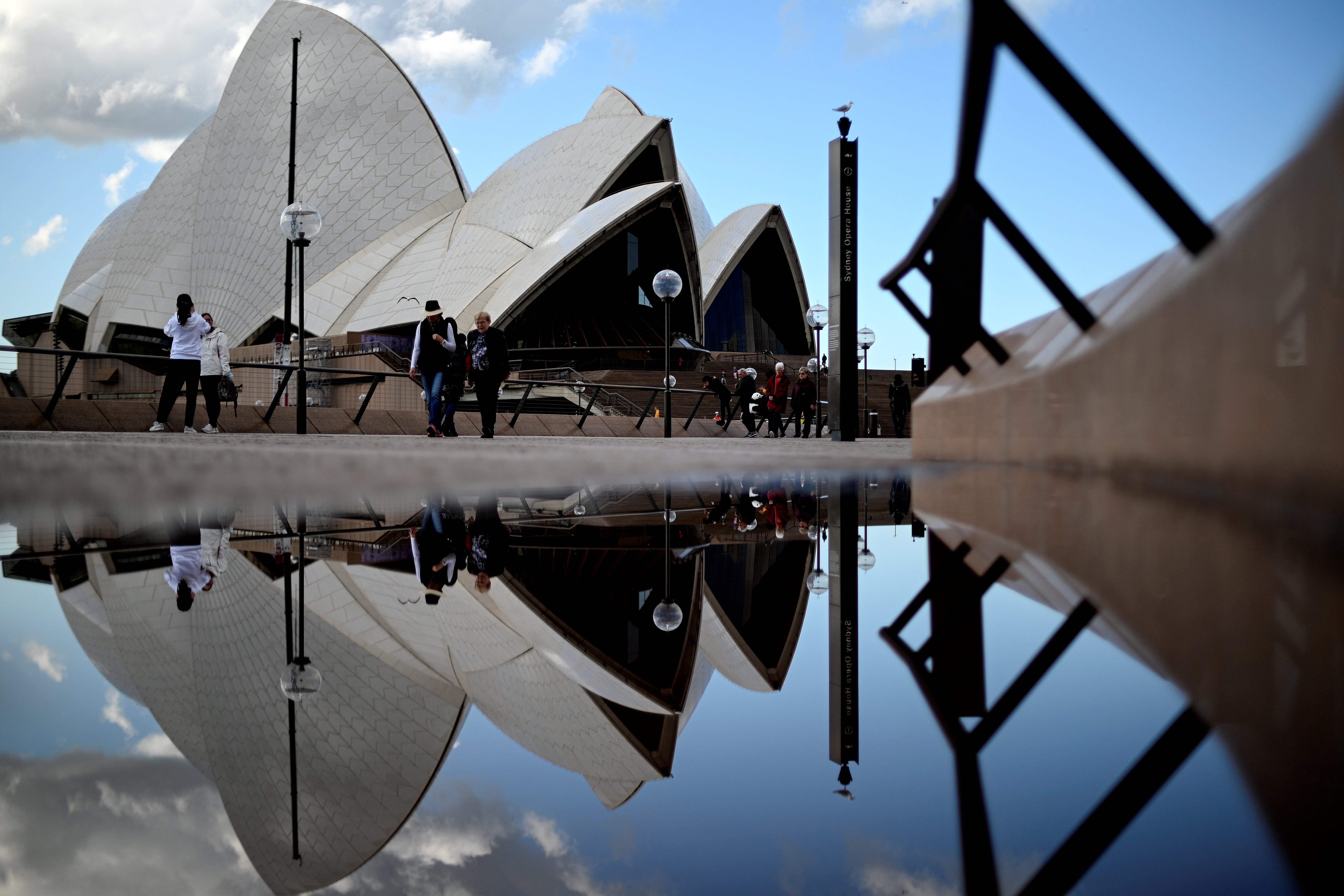 Warga berjalan di sekitar Opera House yang menjadi ikon Australia di Kota Sydney, Australia.