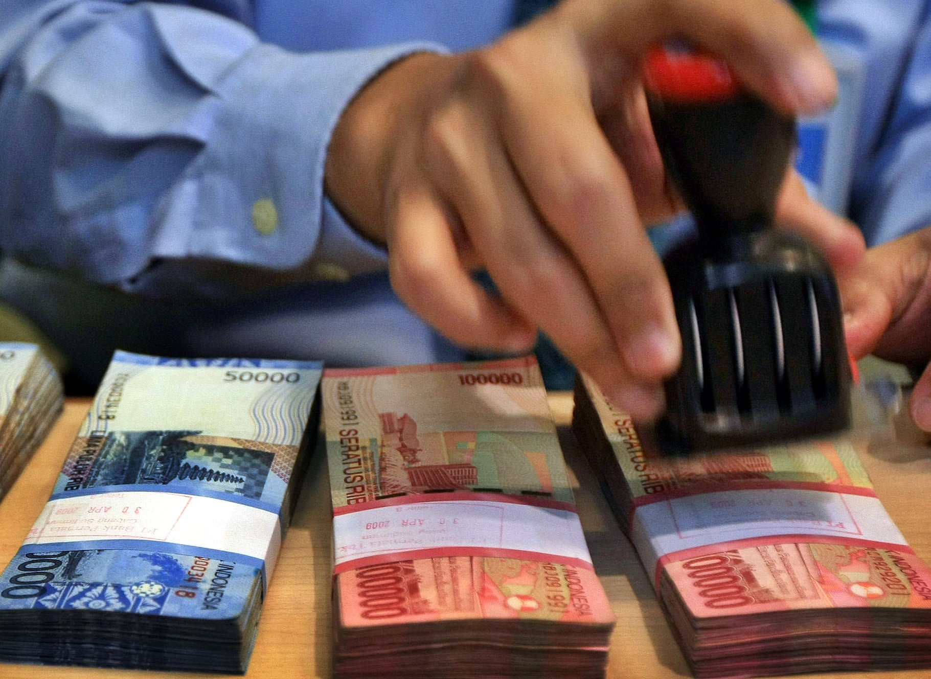 Seorang petugas bank tengah memberi tanda nilai nominal uang rupiah disalah satu bank di Jakarta