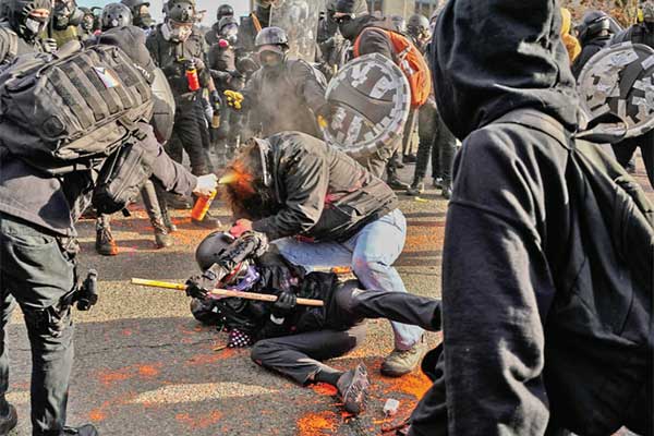 Seorang kontrapendemo menyemprotkan cairan bear mace kepada pendukung Trump saat unjuk rasa di Olympia, AS