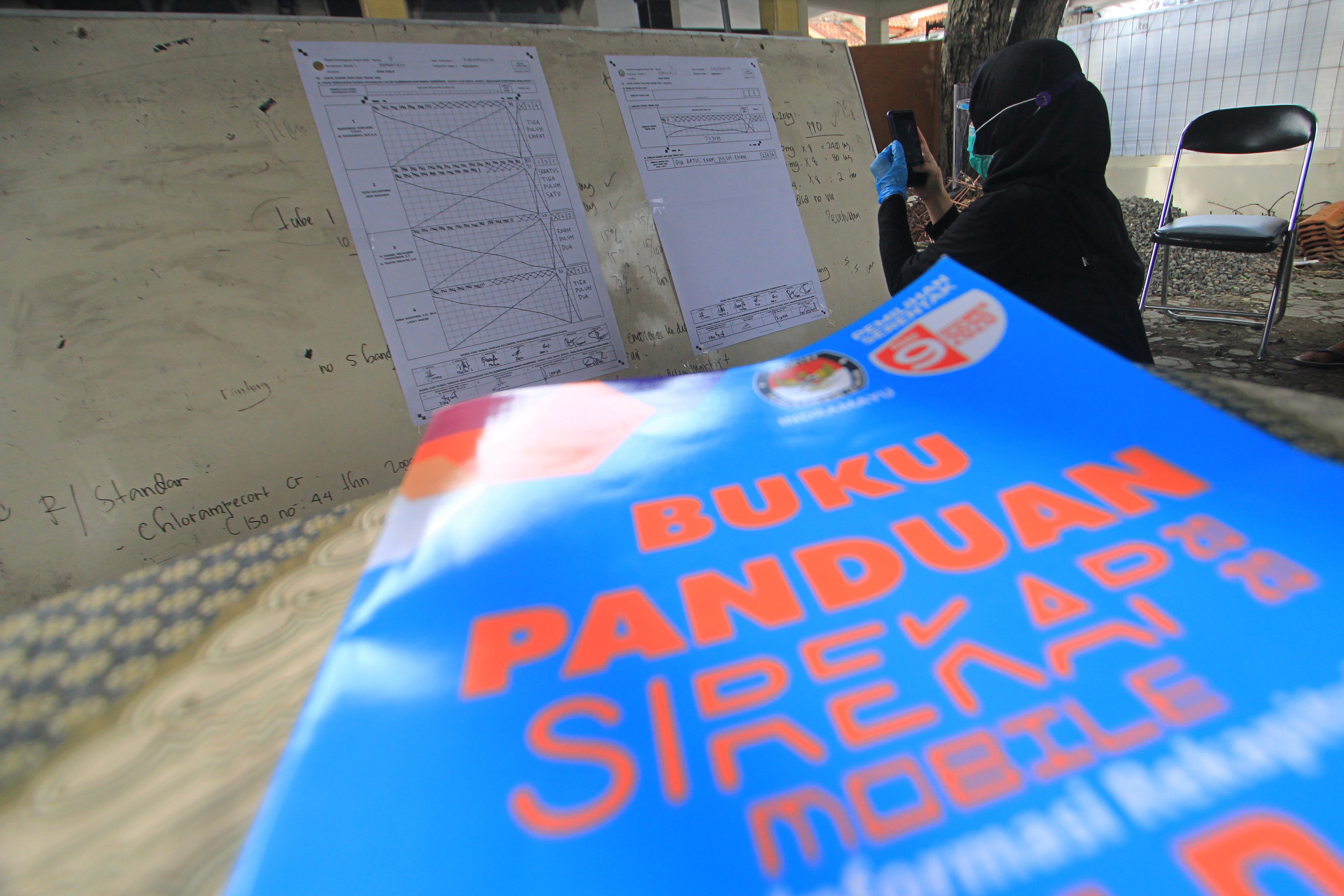 Petugas KPPS mendokumentasikan formulir C1 saat rekapitulasi penghitungan suara dengan menggunakan Sirekap