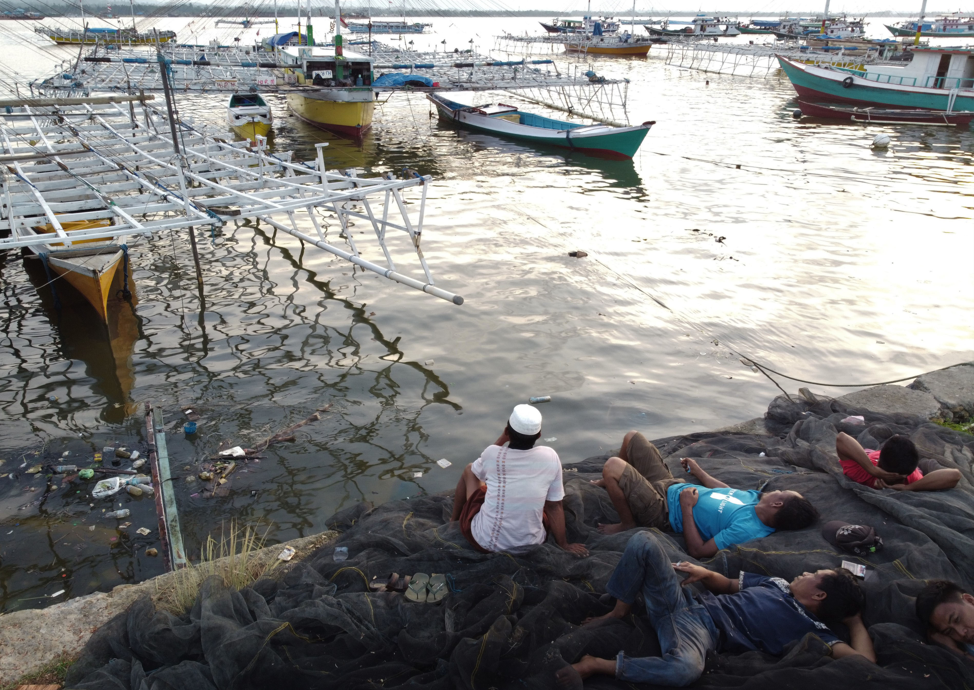 TIDAK MELAUT: Sejumlah nelayan berbaring di atas jaring ikan di Teluk Kendari. Mereka telah sepekan tidak melaut akibat gelombang tinggi.