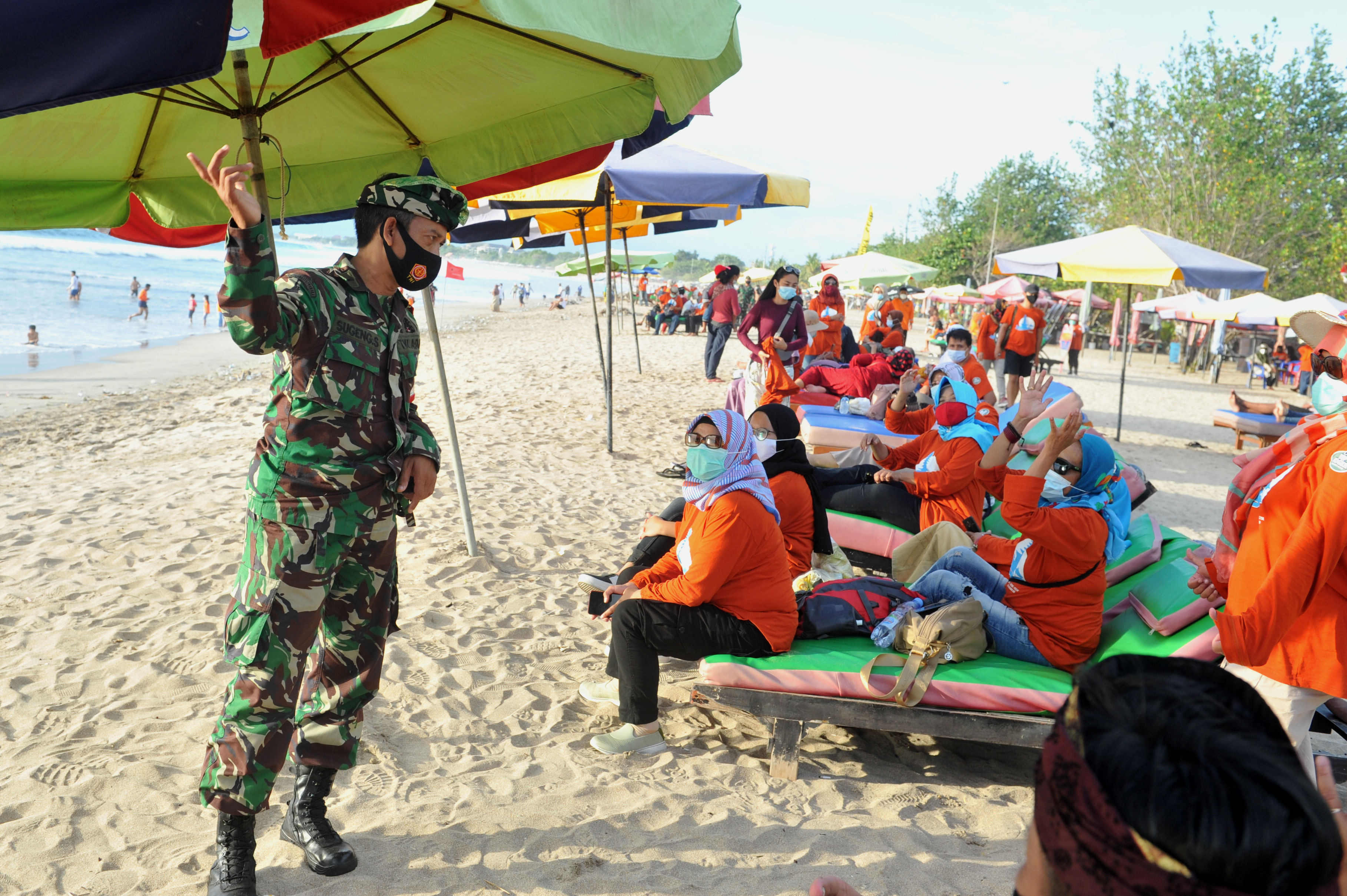 Prajurit TNI mengimbau wisatawan untuk selalu menerapkan protokol kesehatan di Pantai Kuta, Bali.