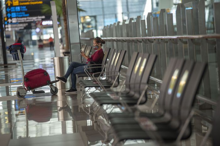 Ilustrasi penumpang menunggu di bandara, menunggu jadwal keberangkatan pesawat.