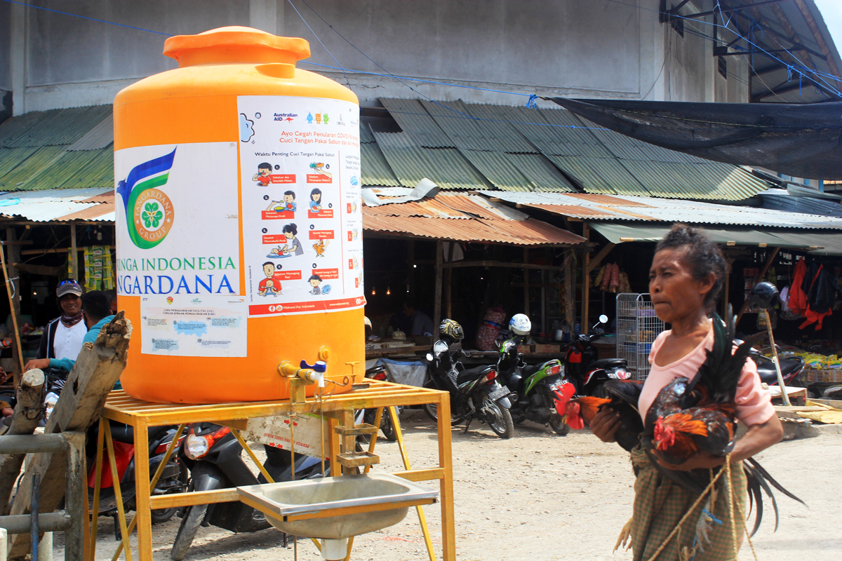Pengunjung Pasar Kasih di Kota Kupang, NTT melintas dekat tempat cuci tangan tanpa tanpa mengenakan masker, beberapa waktu lalu.