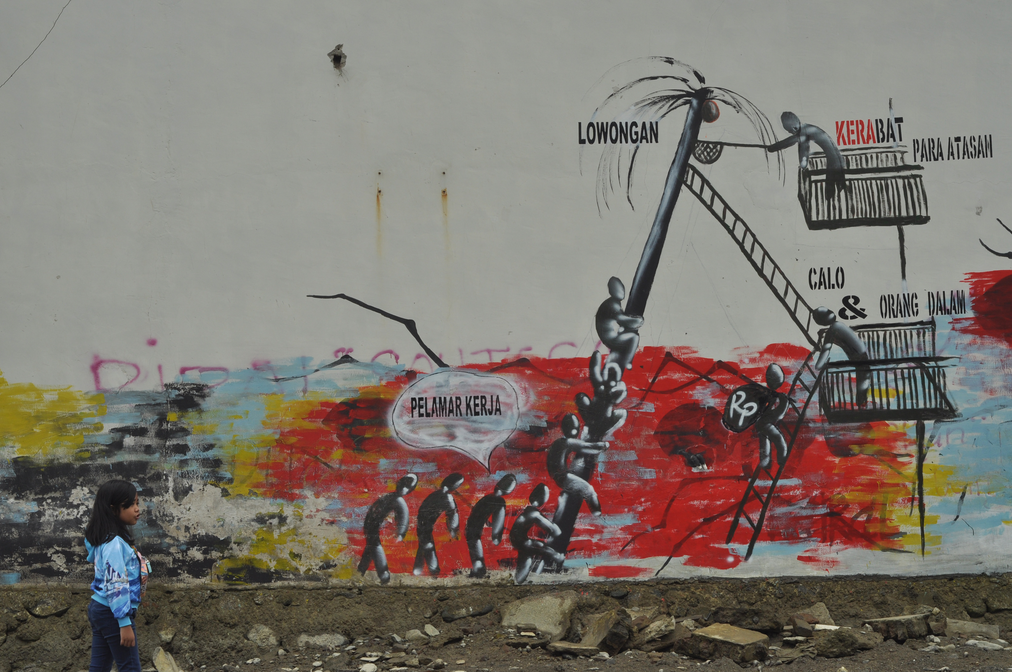 Seorang anak bermain di sekitar mural praktik korupsi di wilayah Palu, Sulawesi Tengah.