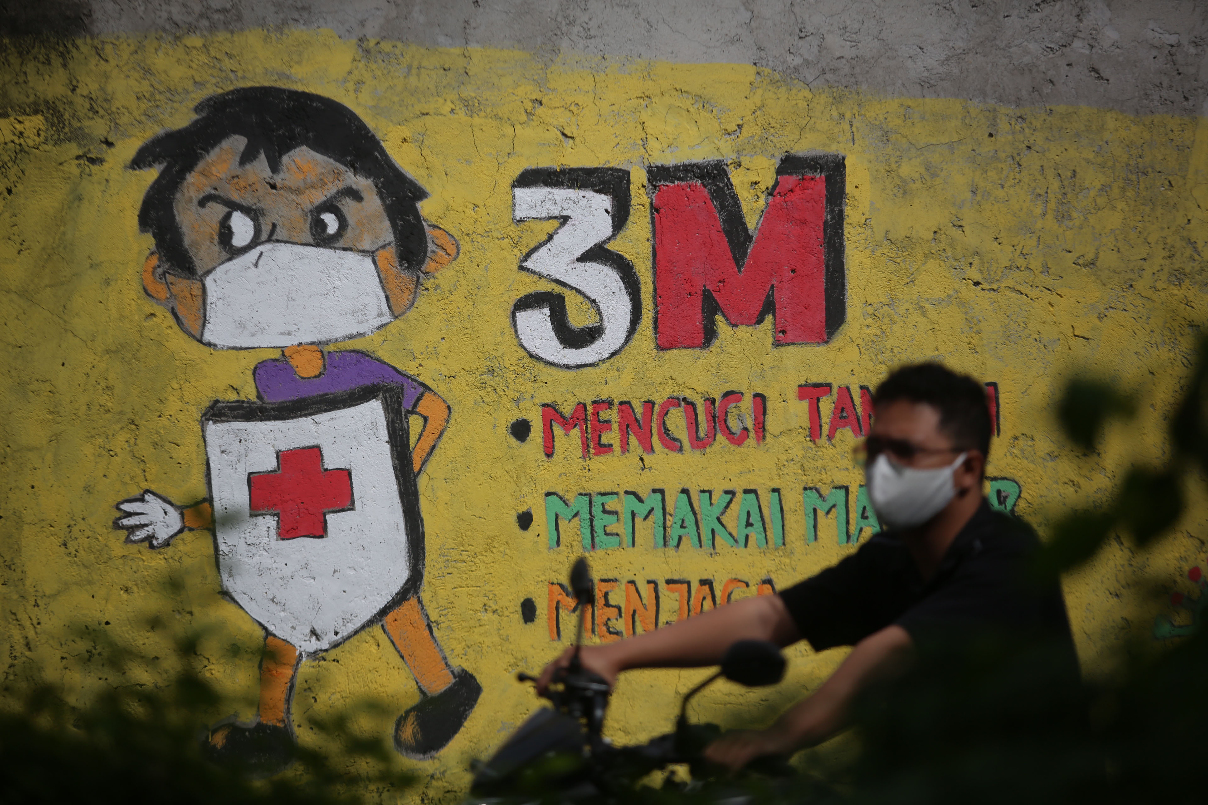 Warga melintasi mural terkait protokol kesehatan di Jakarta. 