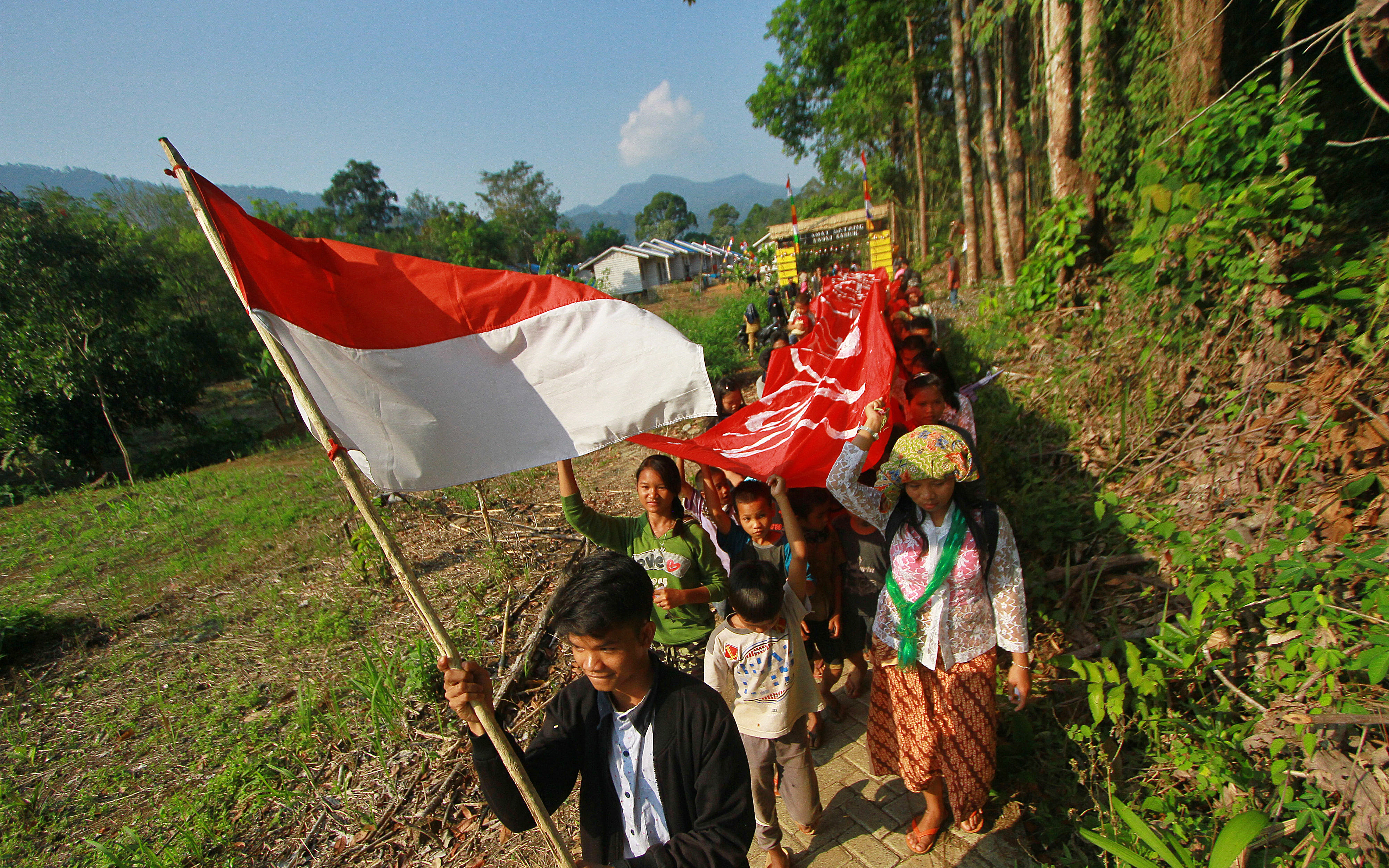  Warga Dayak Meratus berjalan menuju desa dengan membawa bendera Merah Putih pada perayaan HUT Kemerdekaan RI ke-74