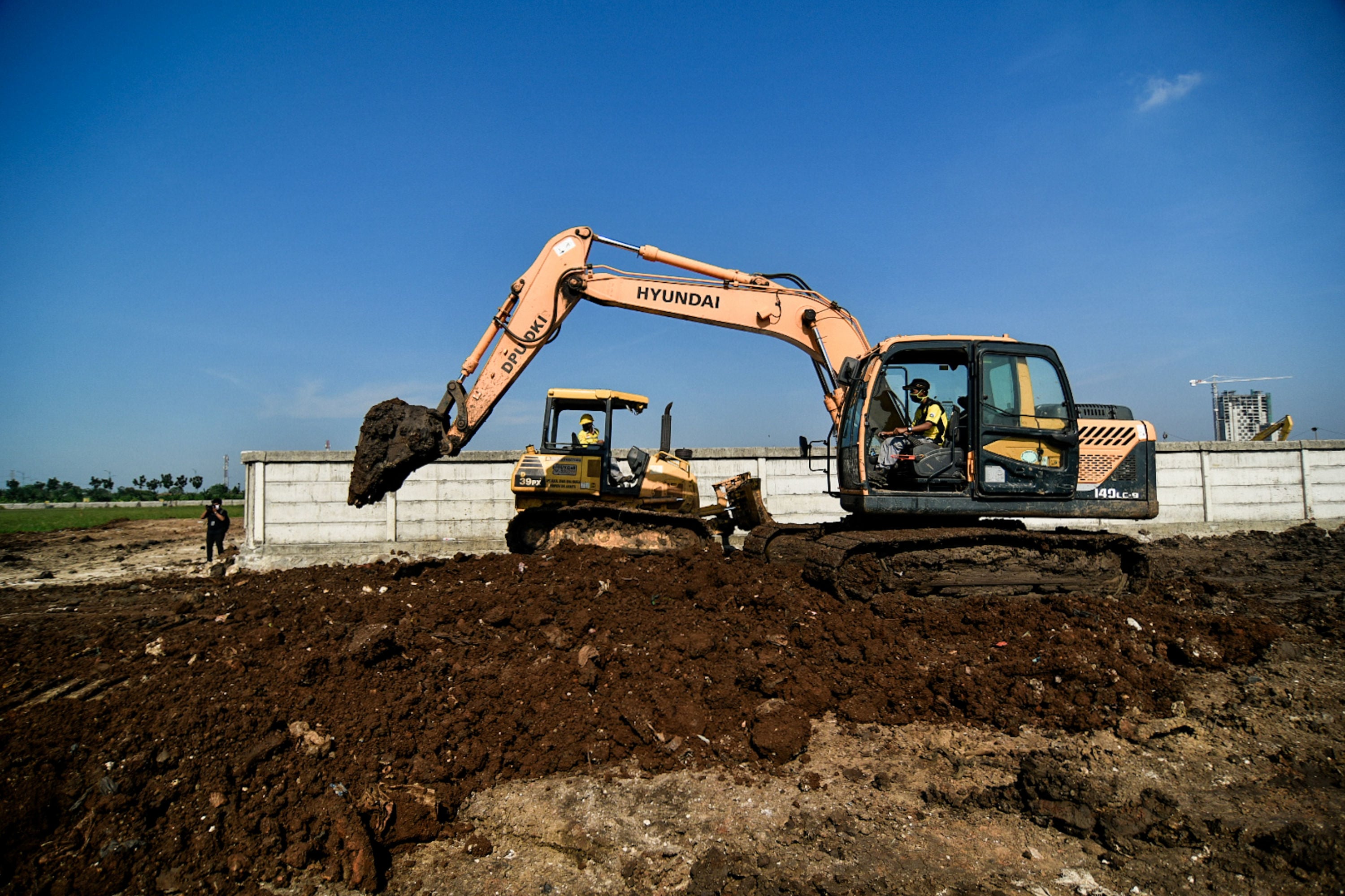Petugas inas Bina Marga menggunakan alat berat saat menyelesaikan penggarapan lahan untuk dijadikan lokasi pemakaman covid-19 di TPU Rorotan