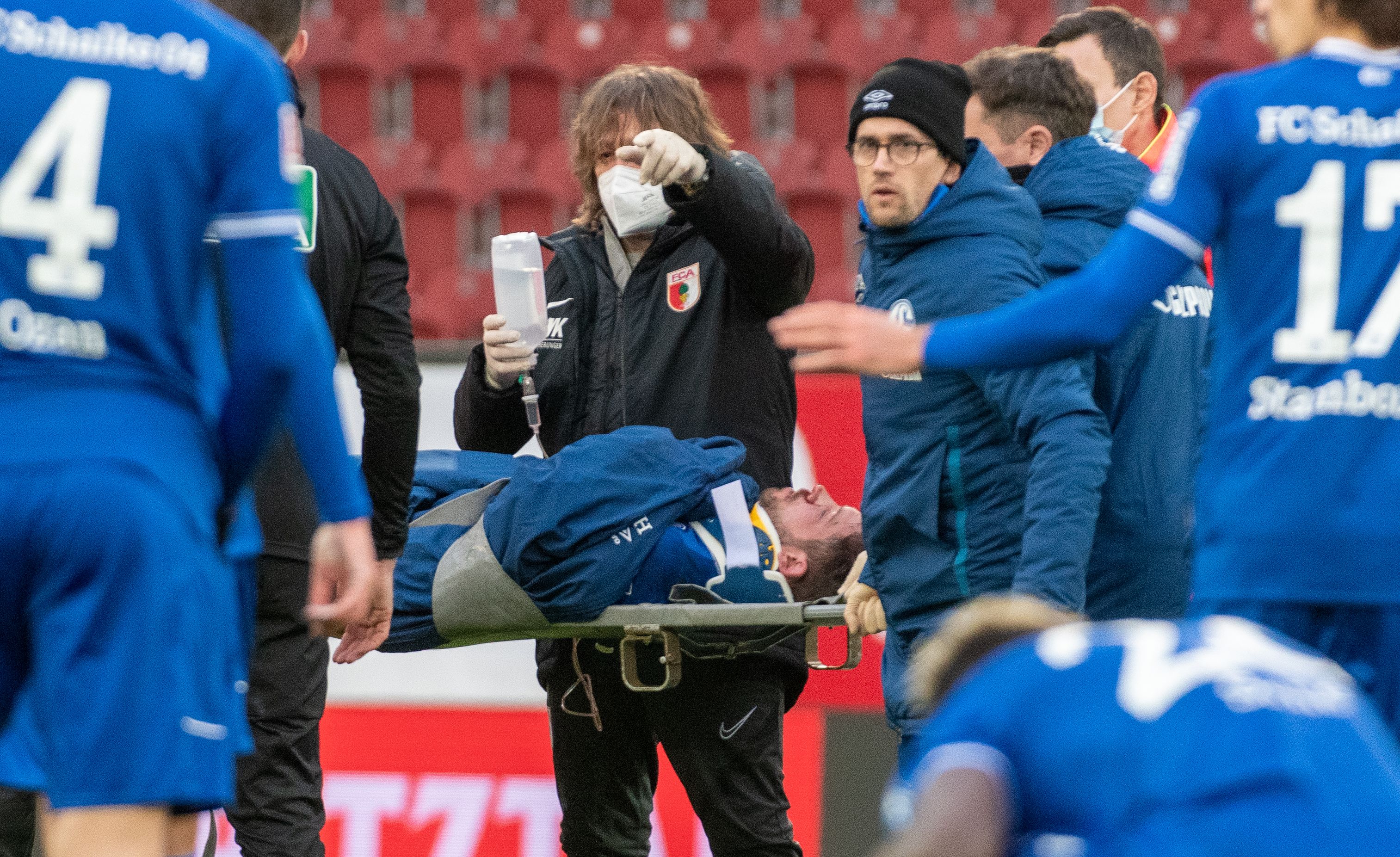 Penyerang Schalke Mark Uth ditandu ke luar lapangan setelah pingsan usai berbenturan kepala dalam laga Bundesliga melawan Augsburg.