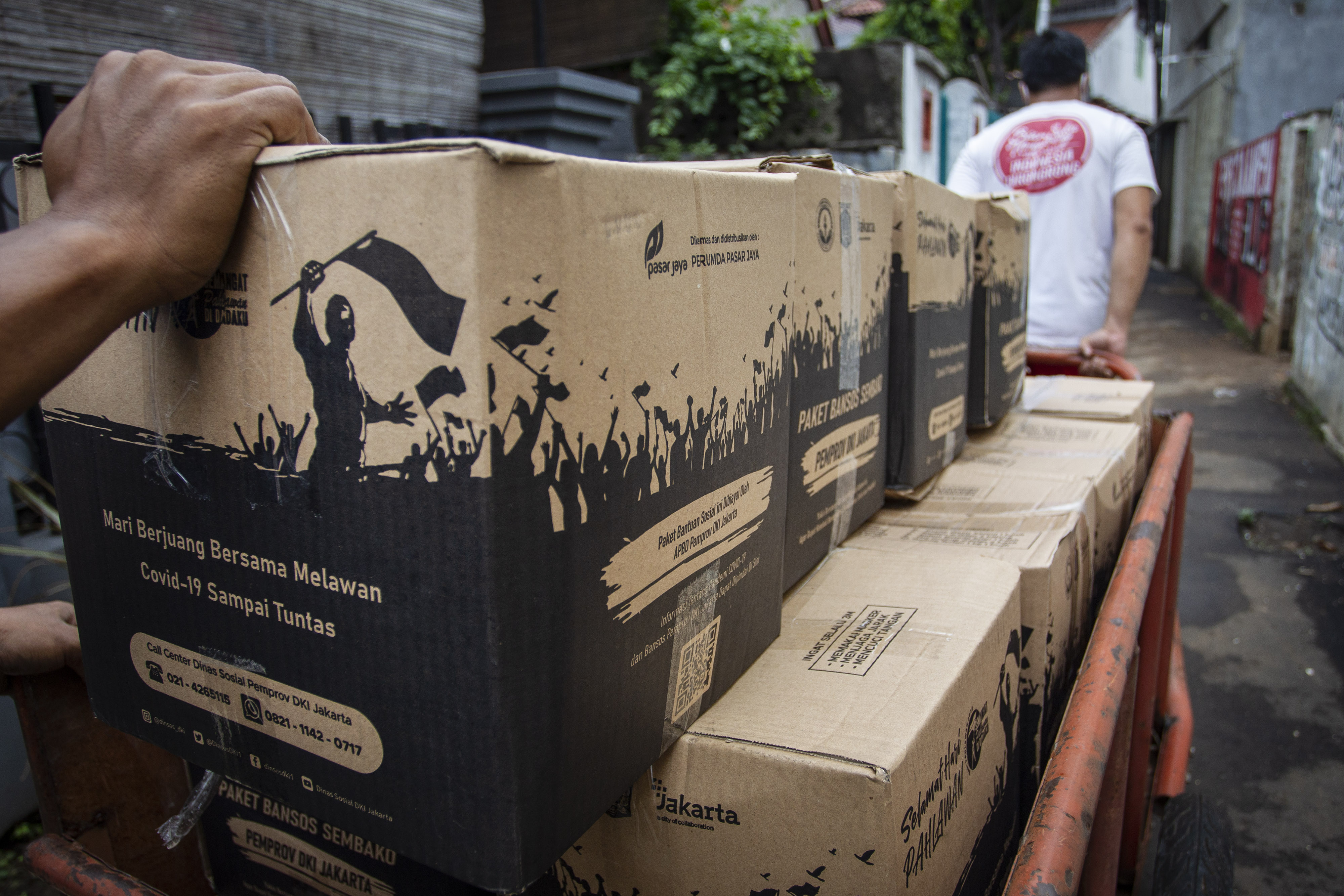 Warga mendistribusikan bansos dari Pemprov DKI Jakarta untuk penanganan covid-19 di Jatinegara, Jakarta Timur, Kamis (5/11/2020). 