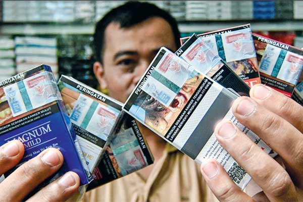 Pedagang menunjukkan bungkus rokok bercukai di Jakarta, kemarin