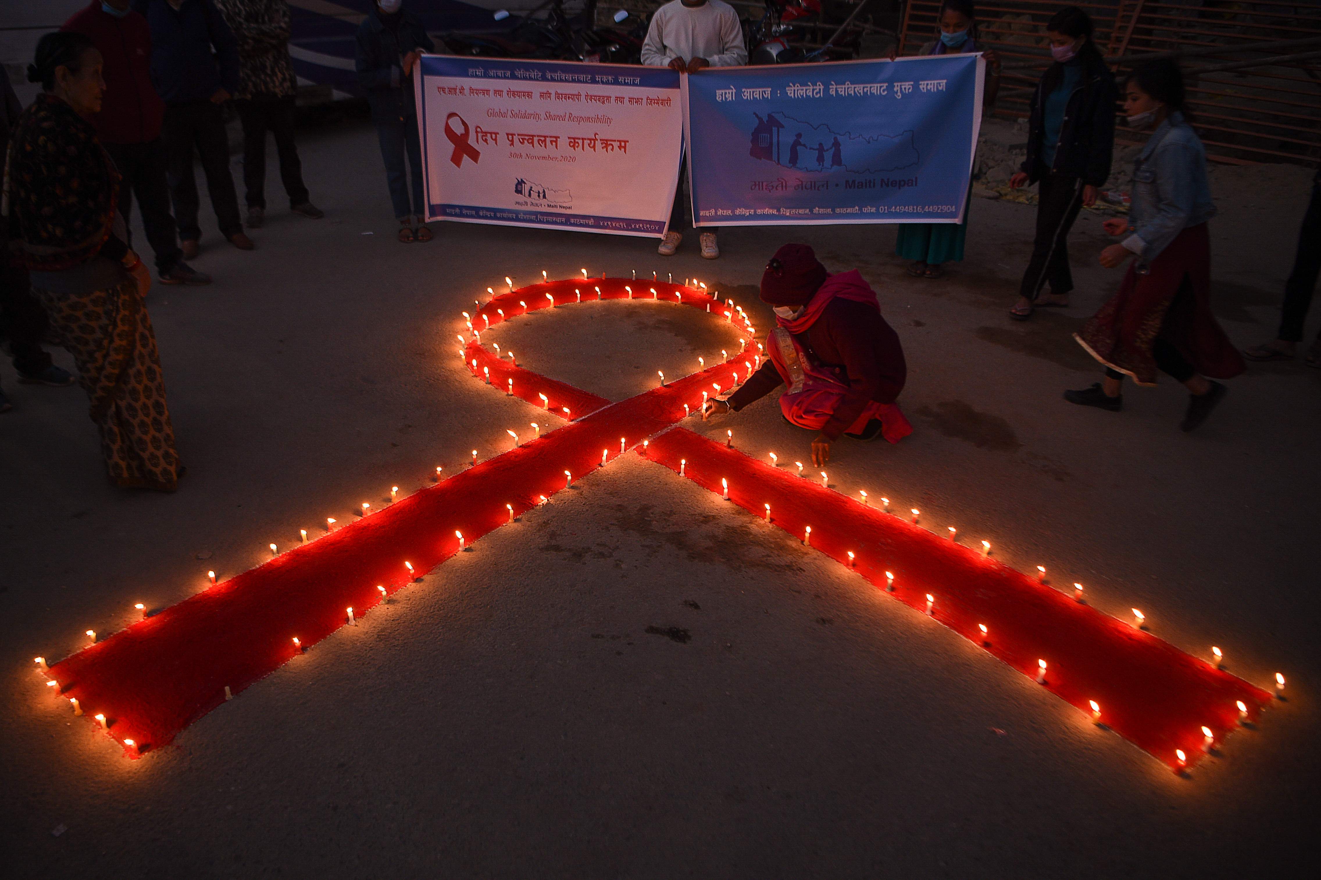 Seorang relawan menyalakan lilin pita merah selama acara peringatan Hari AIDS Internasional di Kathmandu, Nepal Senin (30/11).