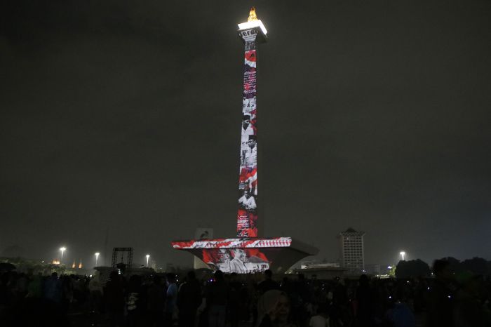 Pengunjung menyaksikan pertunjukan video mapping malam tahun baru di Monas, Jakarta, Selasa (31/12) malam. 