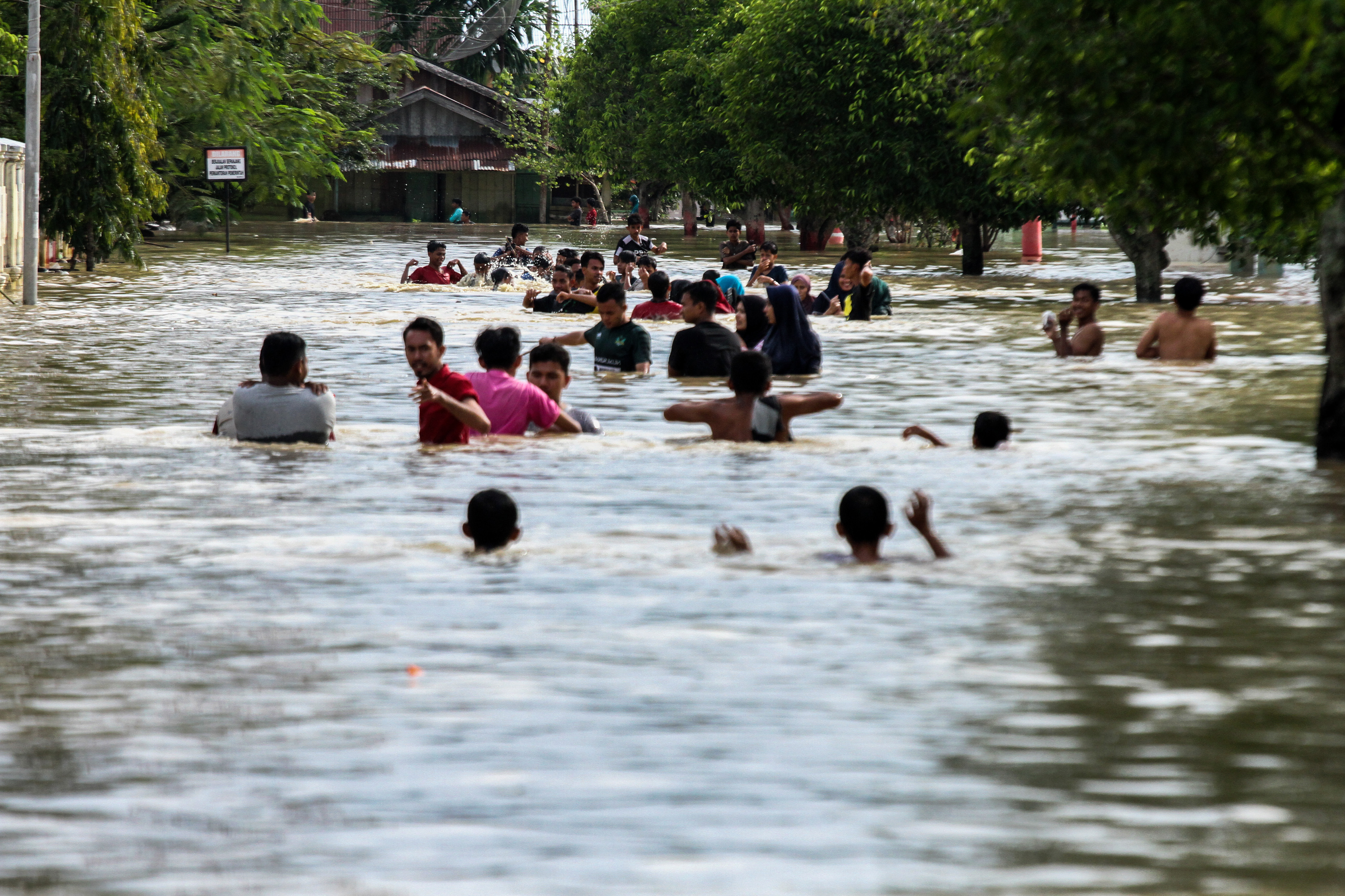 Sejumlah warga mengarungi banjir yang merendam ibukota Lhoksukon, Aceh Utara, Aceh, Senin (7/12/2020).