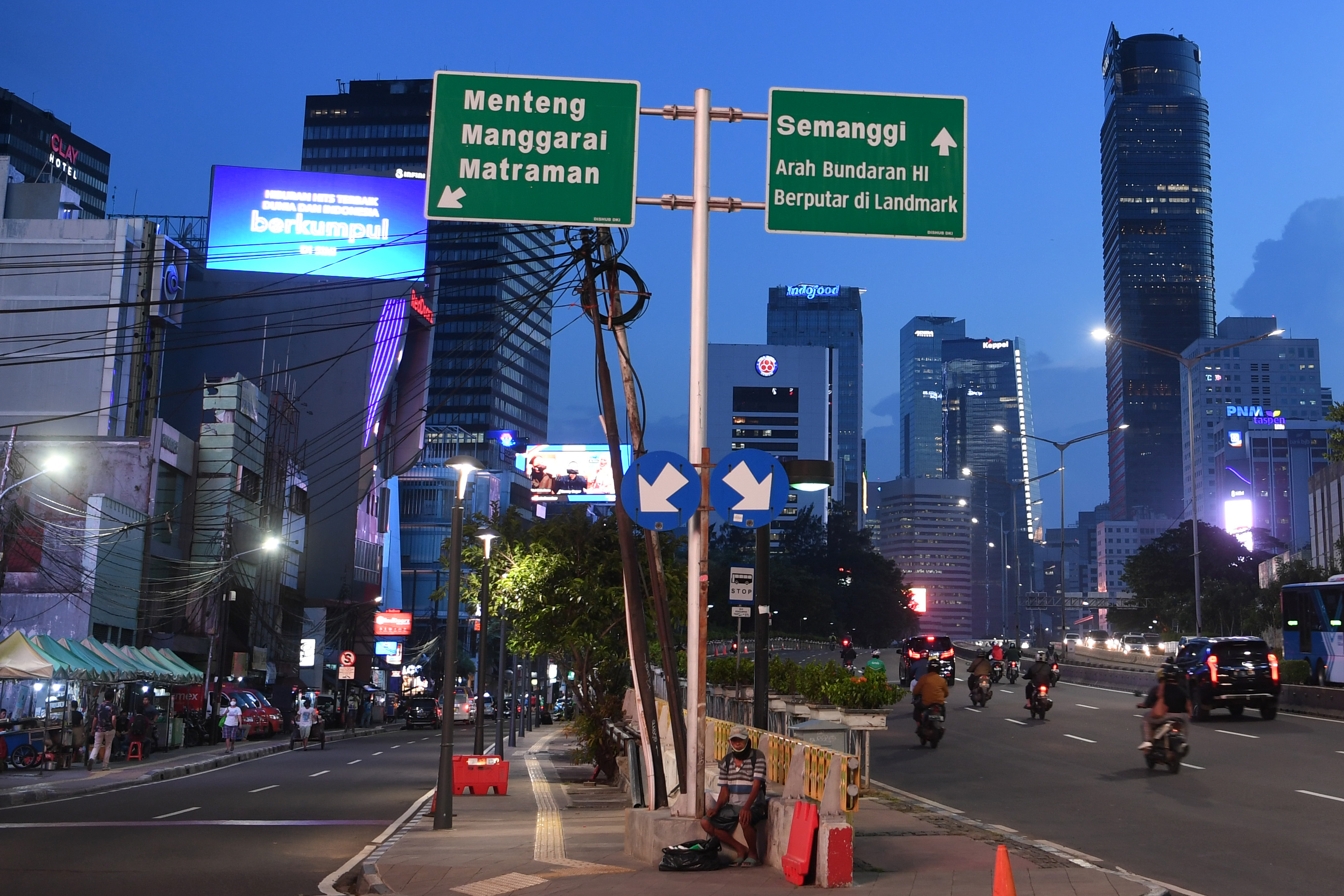 Seorang warga yang mengenakan masker duduk di trotoar jalan MH Thamrin Jakarta.