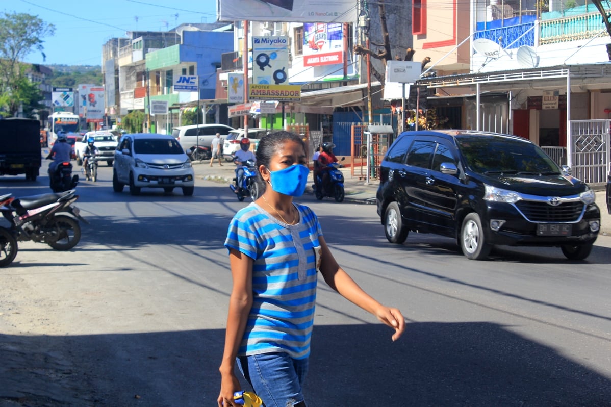  Seorang warga mengenakan masker melintas di ruas Jalan Jenderal Sudirman, Kota Kupang, Nusa Tenggara Timur (NTT), beberapa waktu lalu.