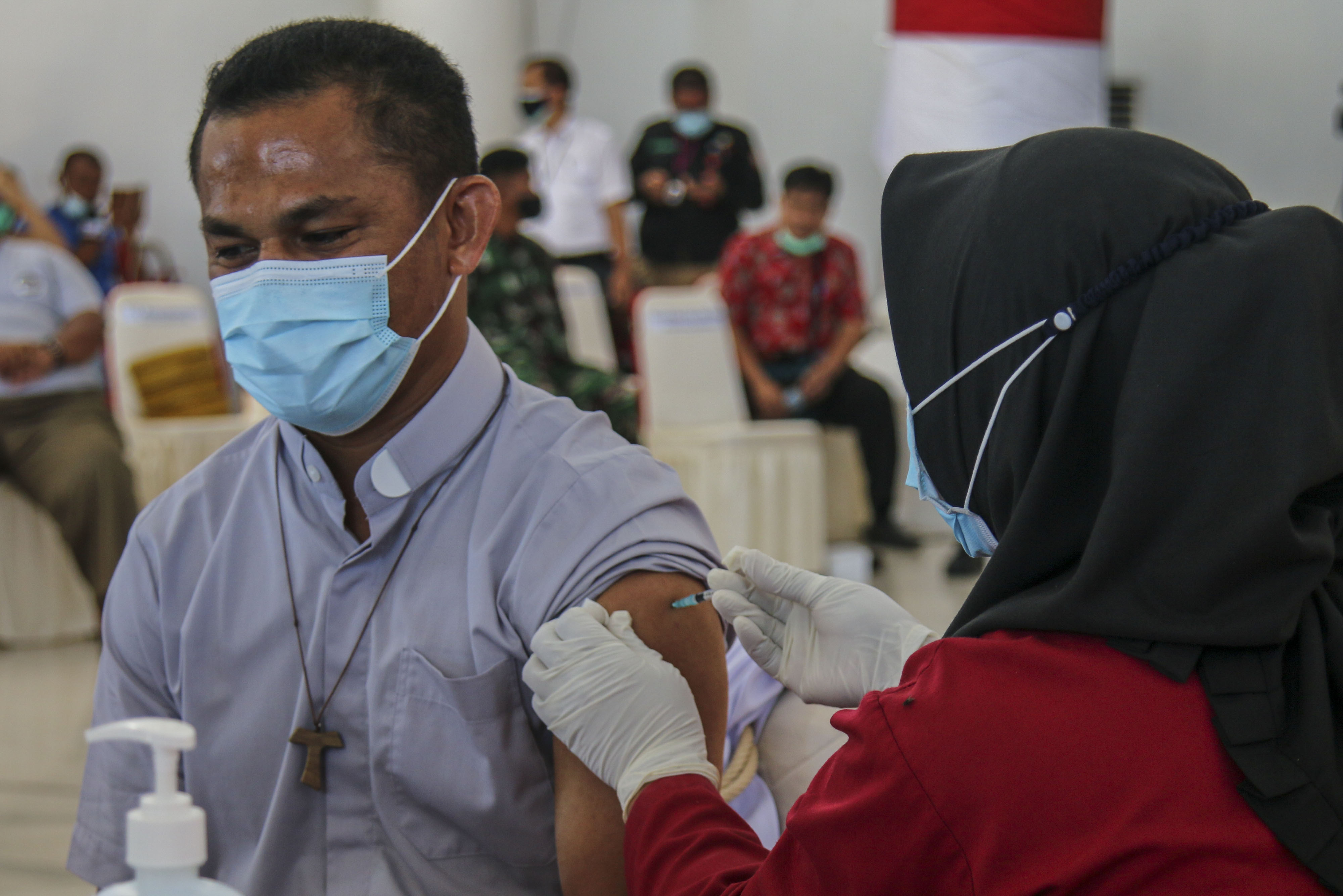 Maksimilianus Dora, Pastor Paroki Santo Stefanus Sempan Timika (kiri) menerima suntikan vaksin covi-19 di Kabupaten Mimika, Papua.