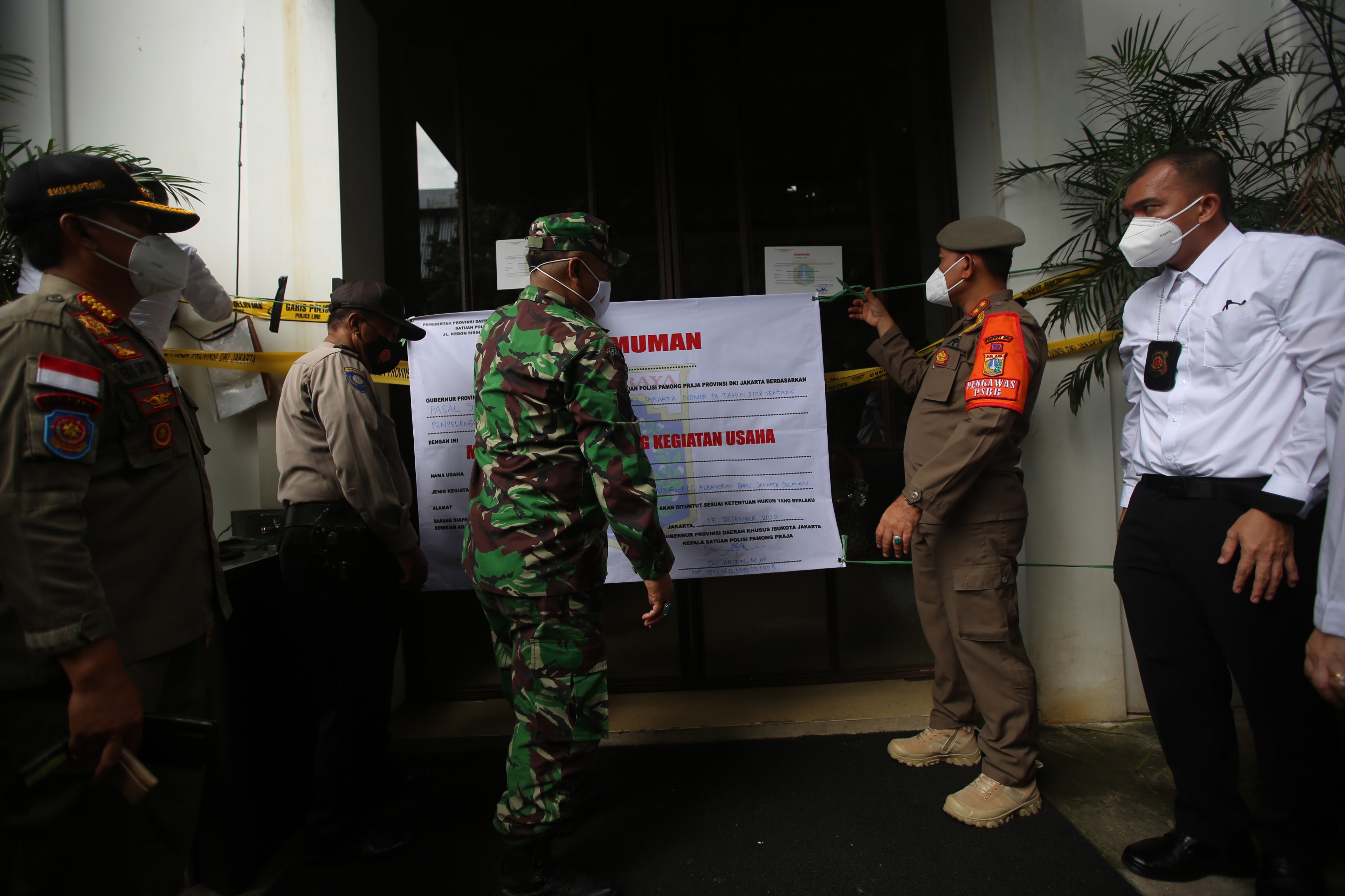 Kasatpol PP DKI Jakarta Arifin (kedua kanan) memasang segel permanen di Kilo Kitchen, Jakarta, Kamis (17/12).
