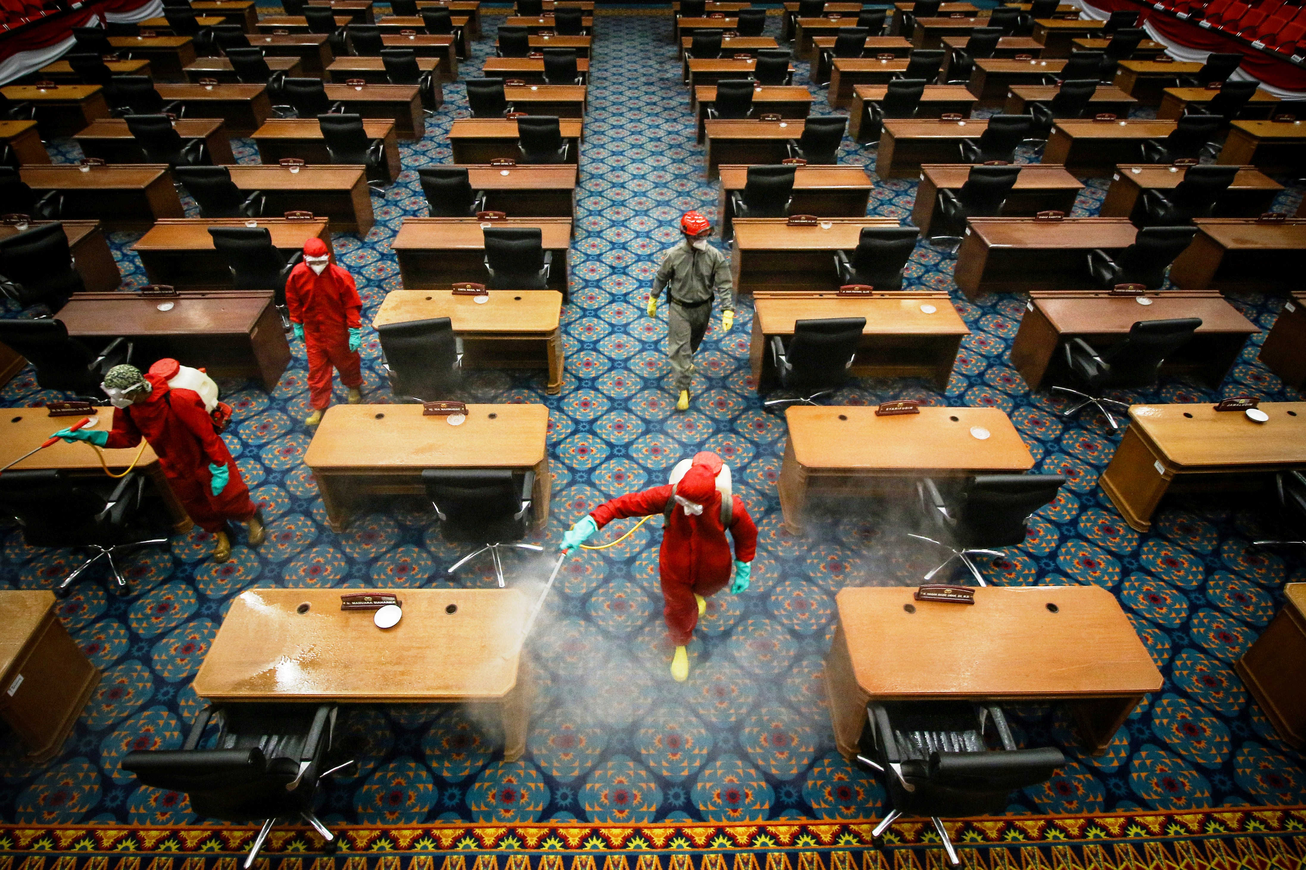 Petugas menyemprotkan cairan disinfektan di ruang sidang paripurna DPRD DKI Jakarta, Rabu (29/7/2020).