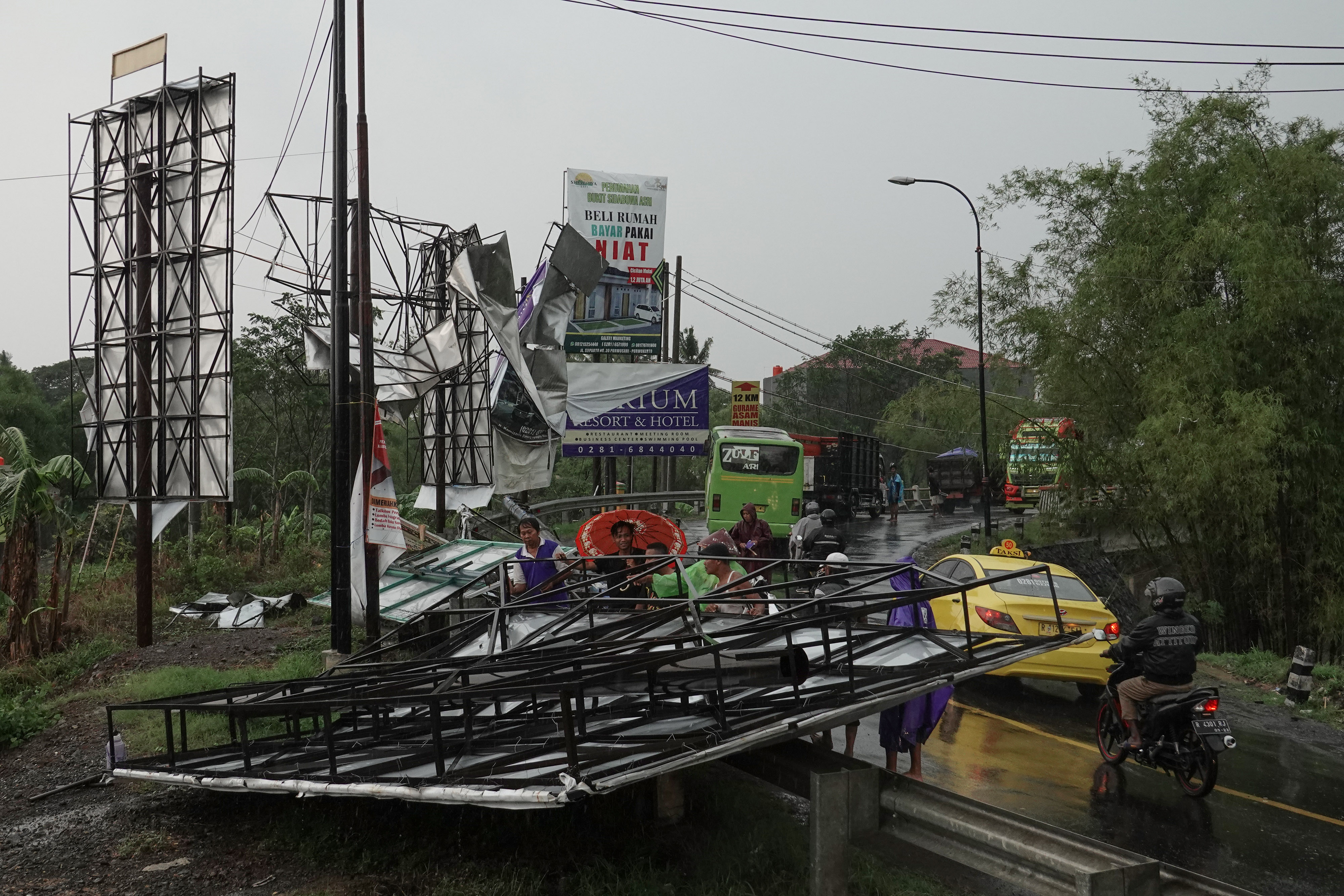 Sejumlah warga meminggirkan rangka baliho yang roboh akibat diterjang angin kencang di Desa Notog, Patikraja, Banyumas, 2019.