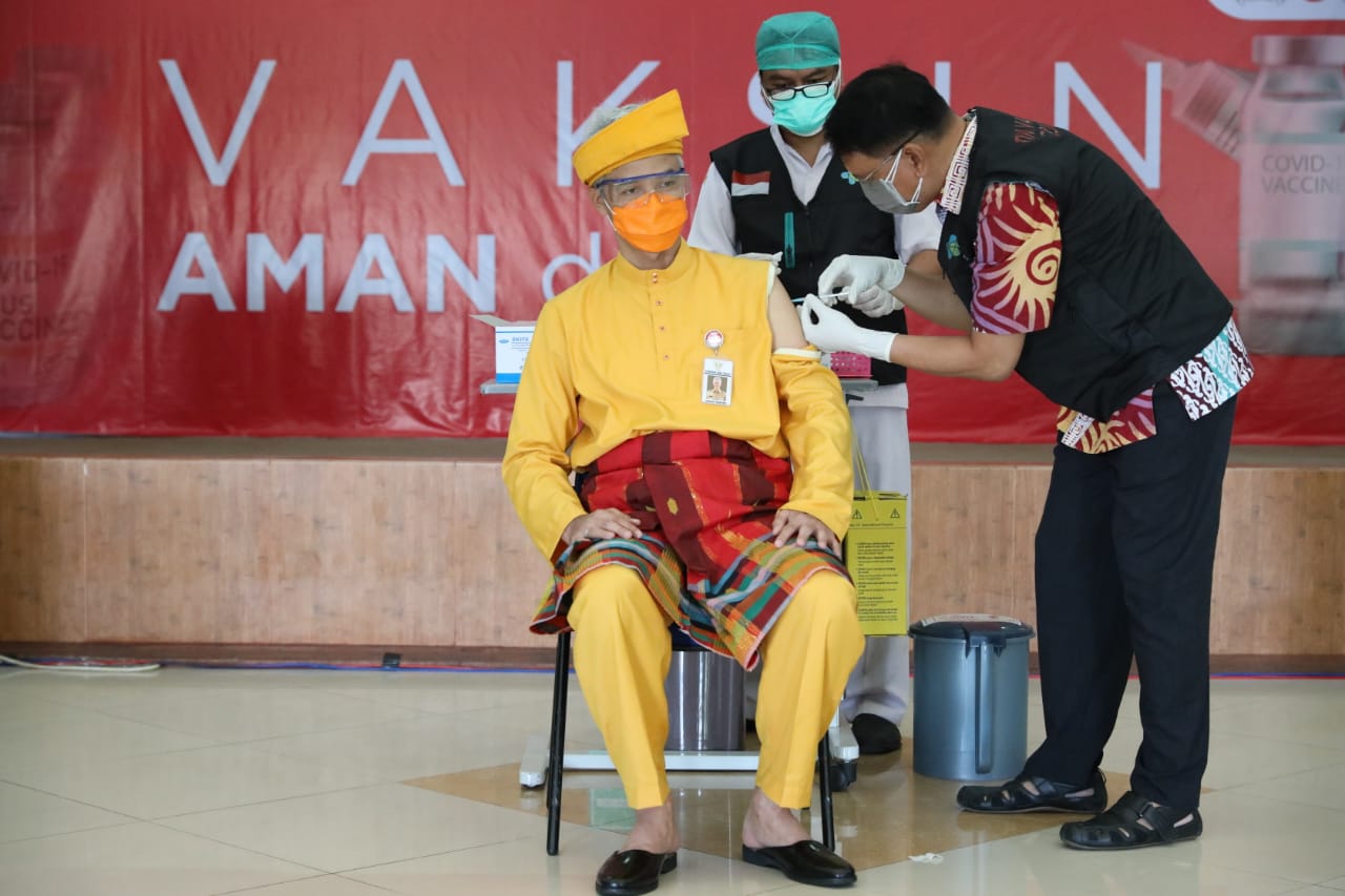 Gubernur Jawa Tengah Ganjar Pranowo memakai baju adat Riau didesain khusus untuk memudahkan saat vaksinasi covid-19 dosis kedua.