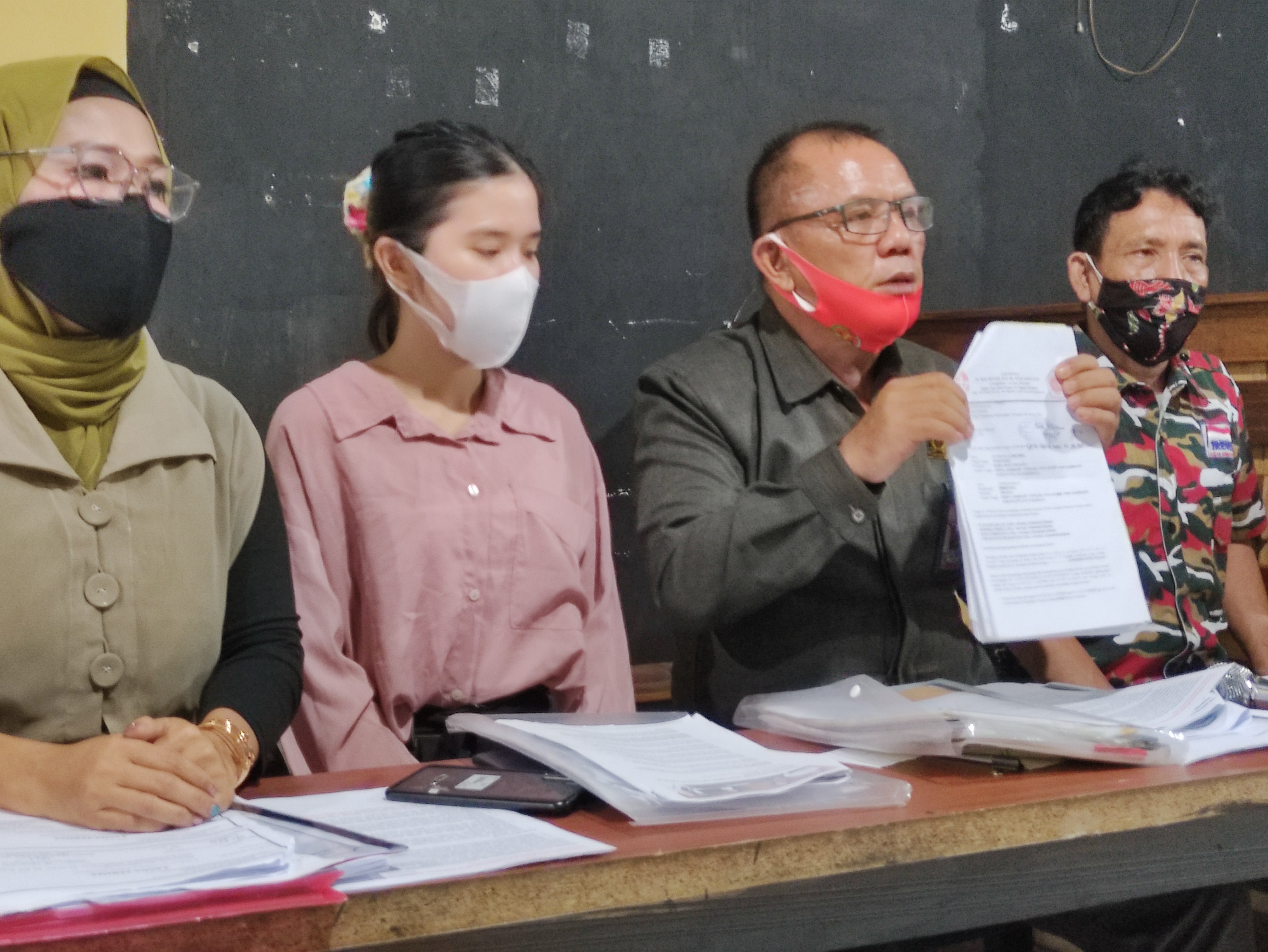 Guntual Laremba memegang kertas putih berisi laporan kepada Kompolnas karena merasa dilecehkan dalam kasus hukum yang menimpanya.