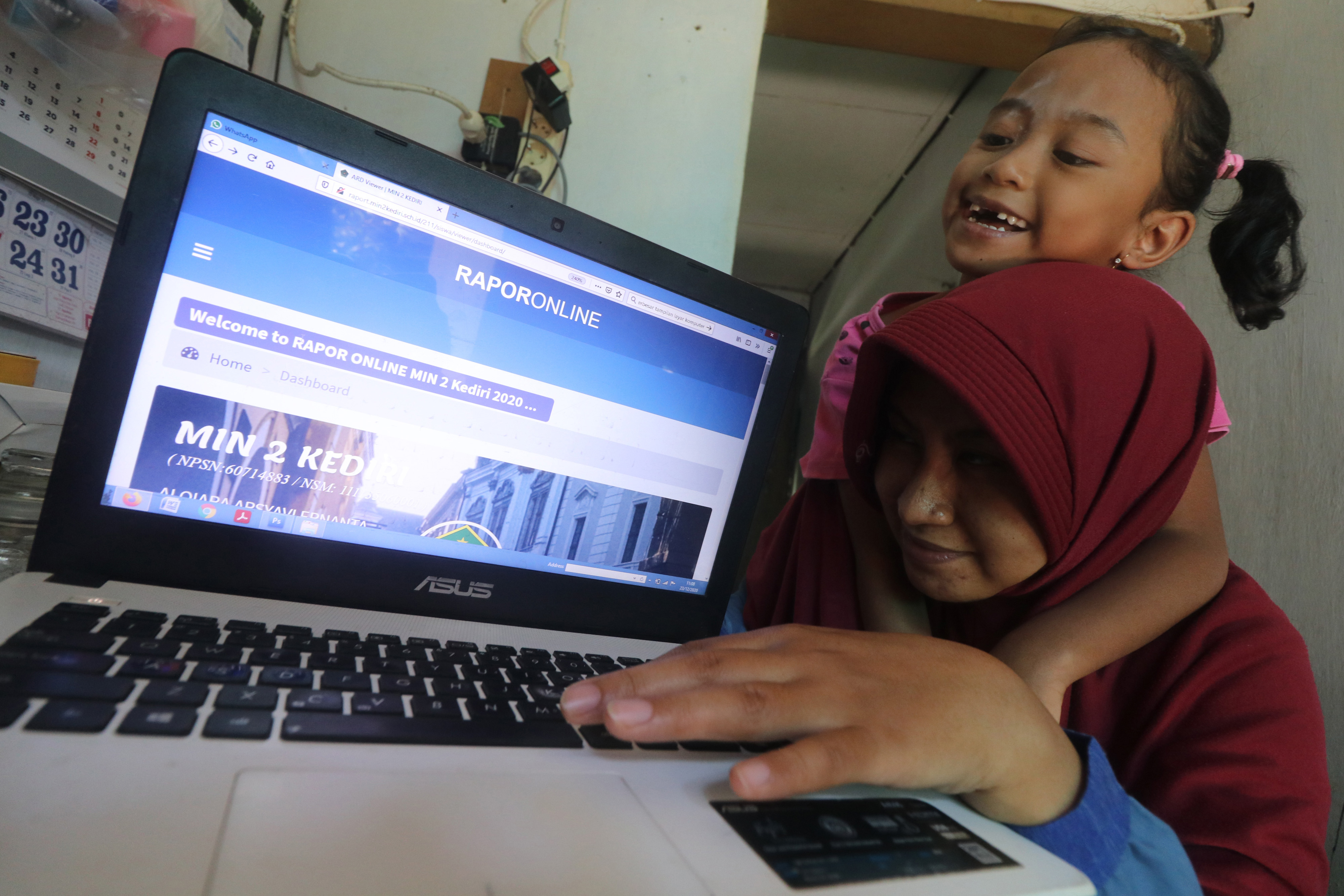  Orang tua bersama anaknya memantau rapor digital Madrasah Ibtidaiyah Negeri 2 Kediri di rumahnya, di Kediri, Rabu (23/12/2020).