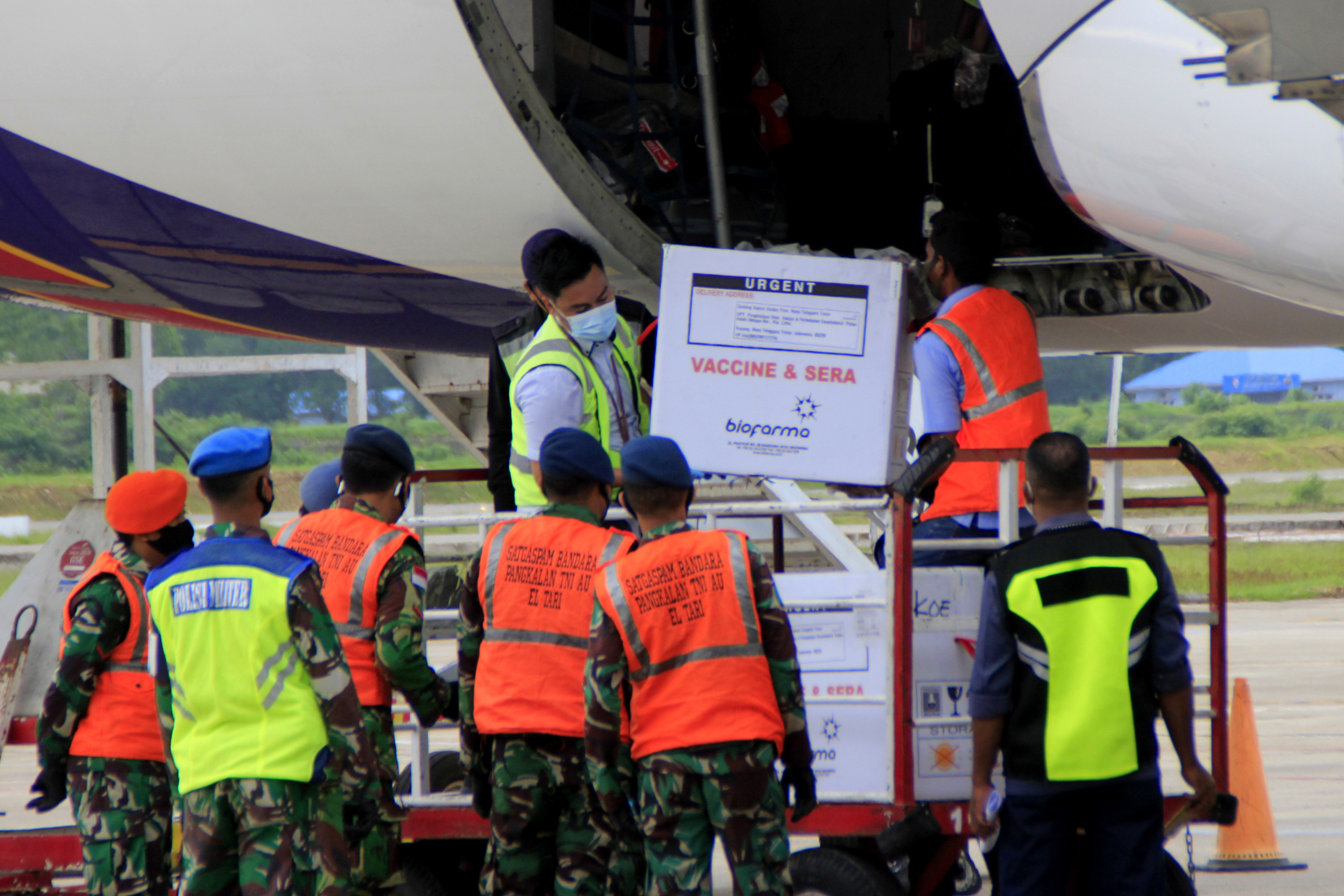 Petugas kargo pesawat menurunkan satu koli vaksin covid-19 Sinovac tahap I di Bandara El Tari Kupang, Kota Kupang, NTT Selasa (5/1/2021)