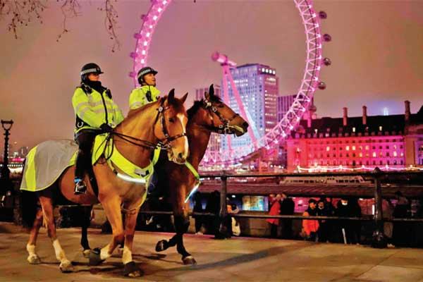 Petugas polisi berpatroli di taman Victoria di seberang London Eye yang hampir sepi pada malam tahun baru di London, Inggris