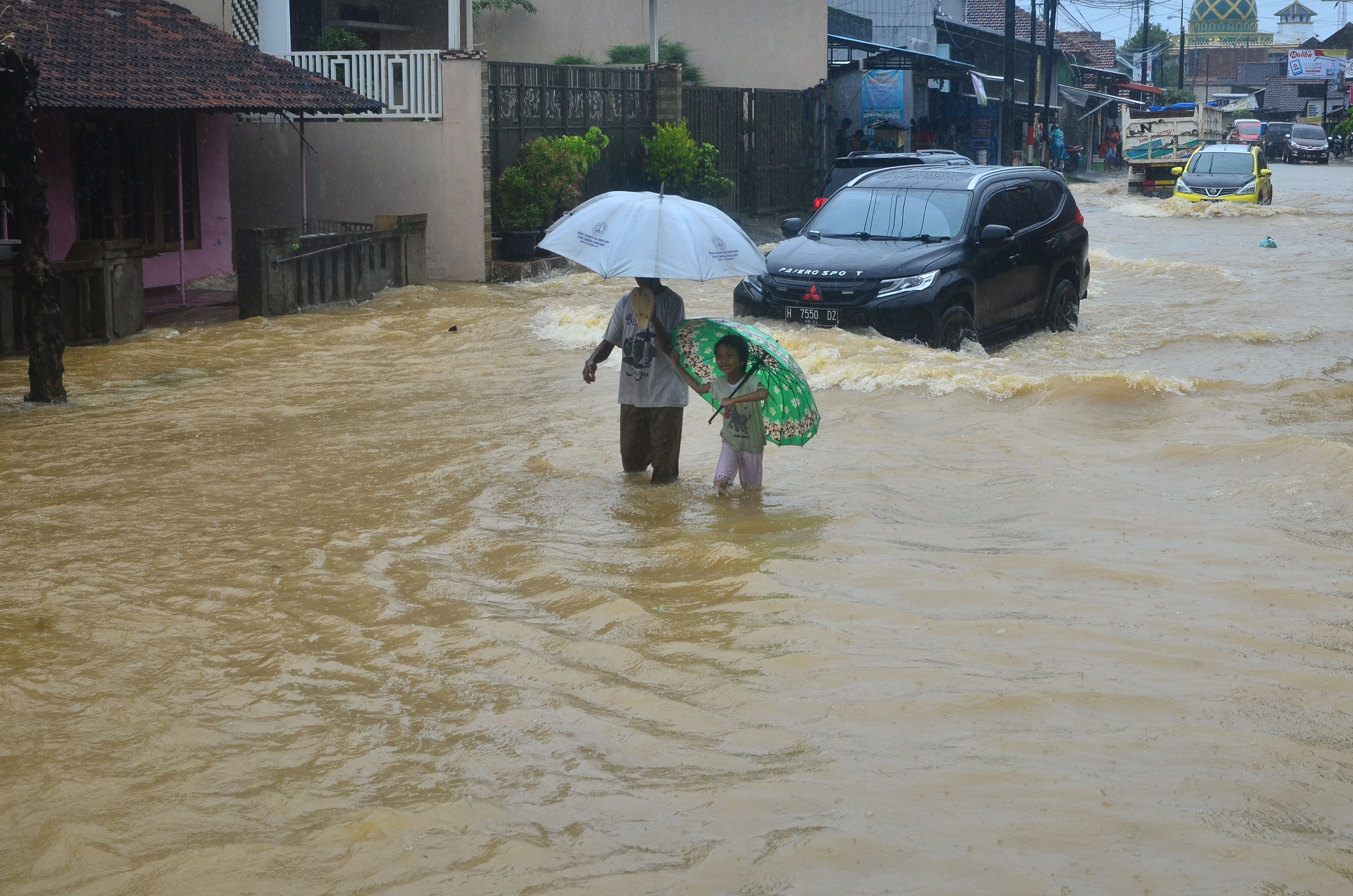 Ilustrasi.Warga melintasi jalan yang tergenang banjir di Desa Mejobo, Mejobo, Kudus, Jawa Tengah, Selasa (19/1)