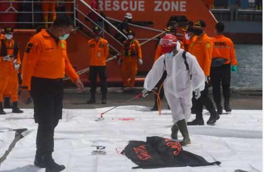 Petugas menyemprotkan disinfektan ke arah kantong jenazah berisi bagian tubuh korban pesawat Sriwijaya Air SJ 182 rute Jakarta - Pontianak.