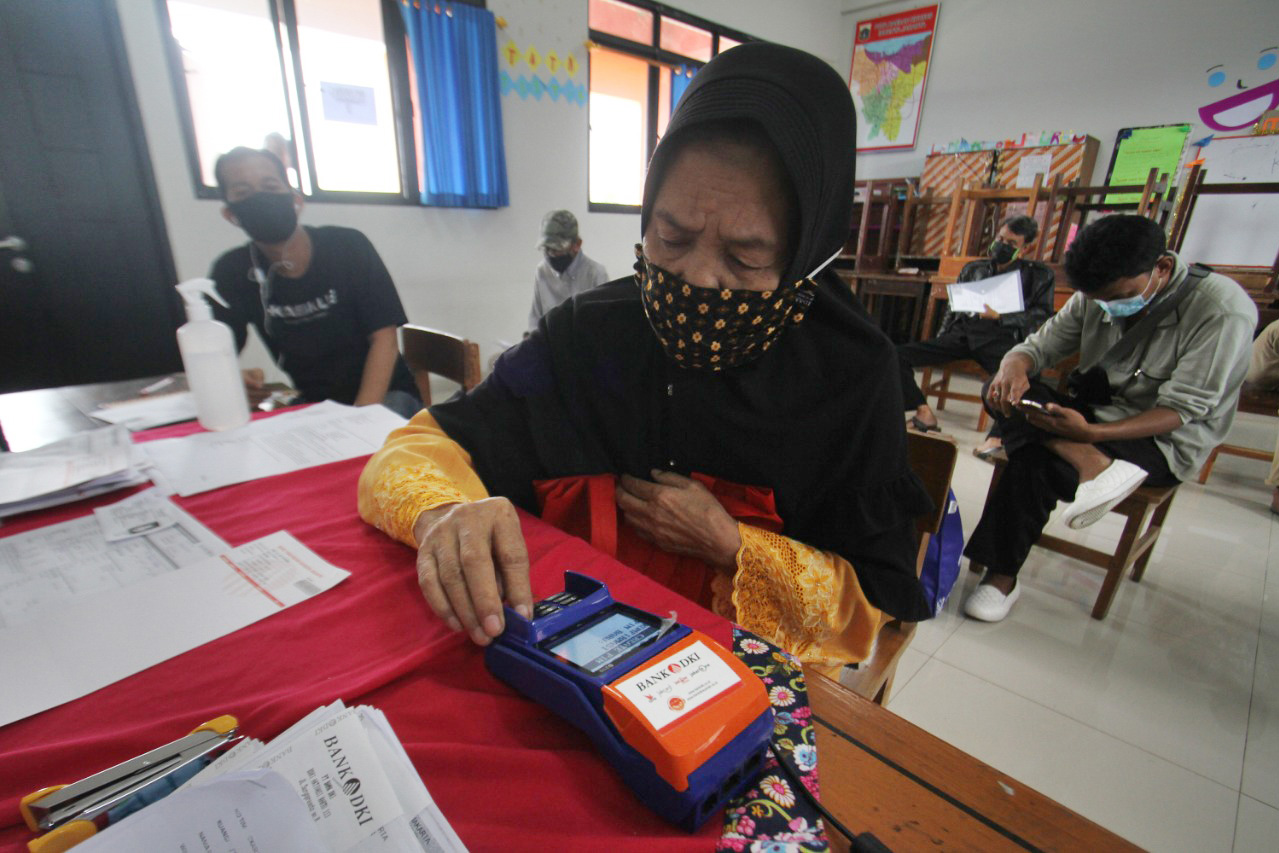 Warga penerima manfaat melakukan registrasi PIN kartu ATM yang merupakan bagian dari tabungan Bansos Jakarta di SDN 13 Lubang Buaya