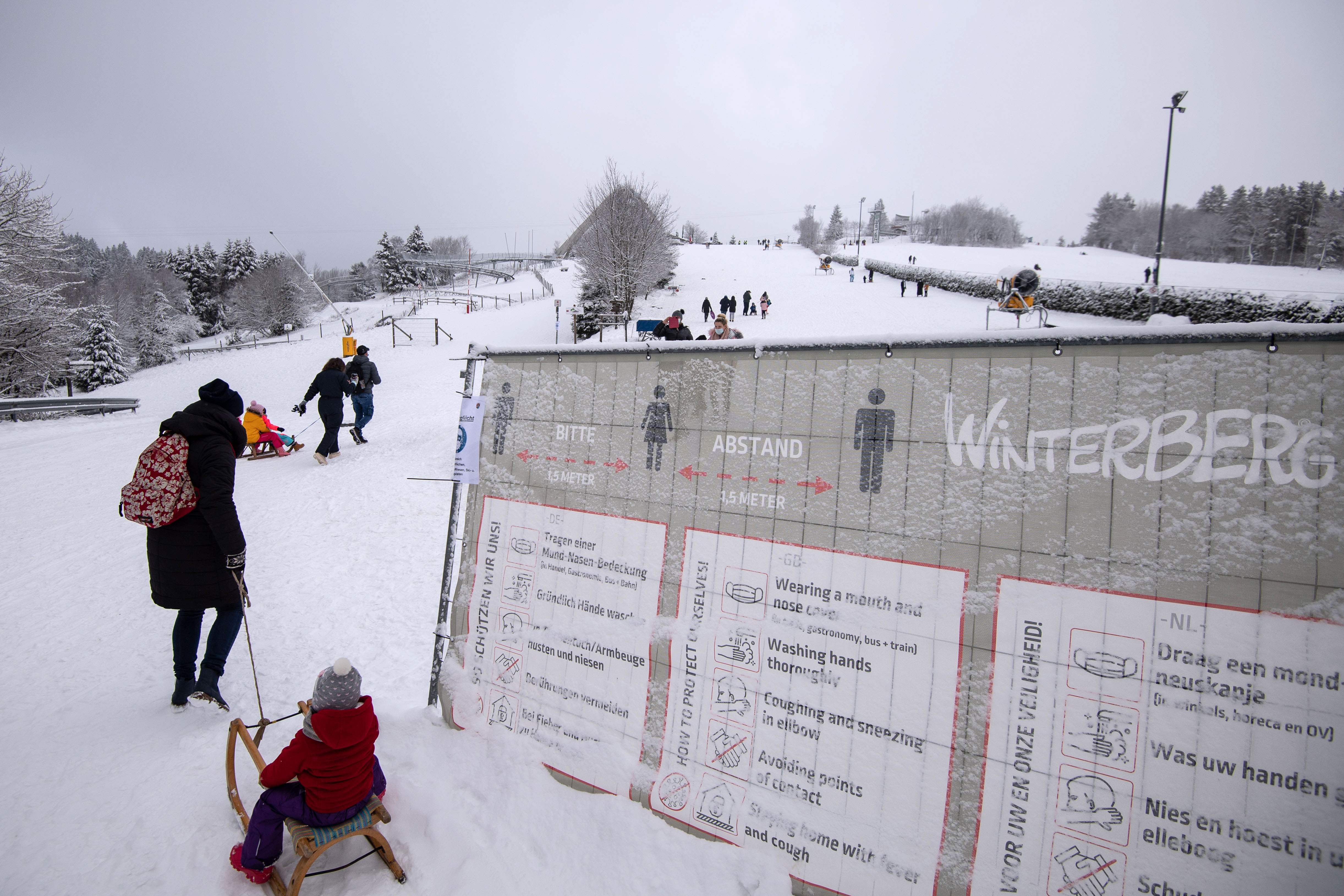 Turis melintas di dekat papan pengumuman protokol kesehatan di Winterberg, Jerman.