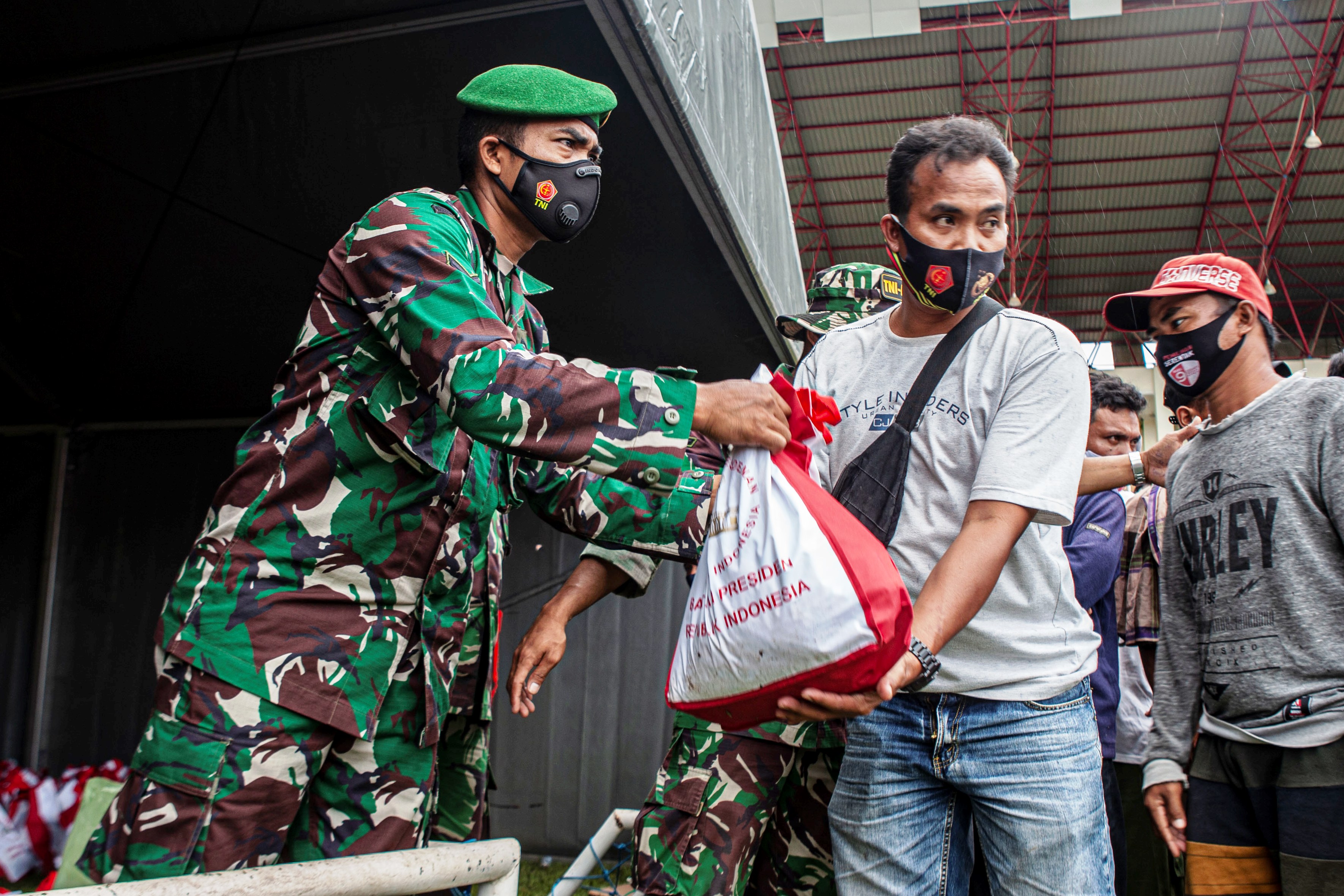 Prajurit TNI membagikan bingkisan berisi sembako dari Presiden Republik Indonesia Joko Widodo kepada pengungsi gempa bumi Sulbar.