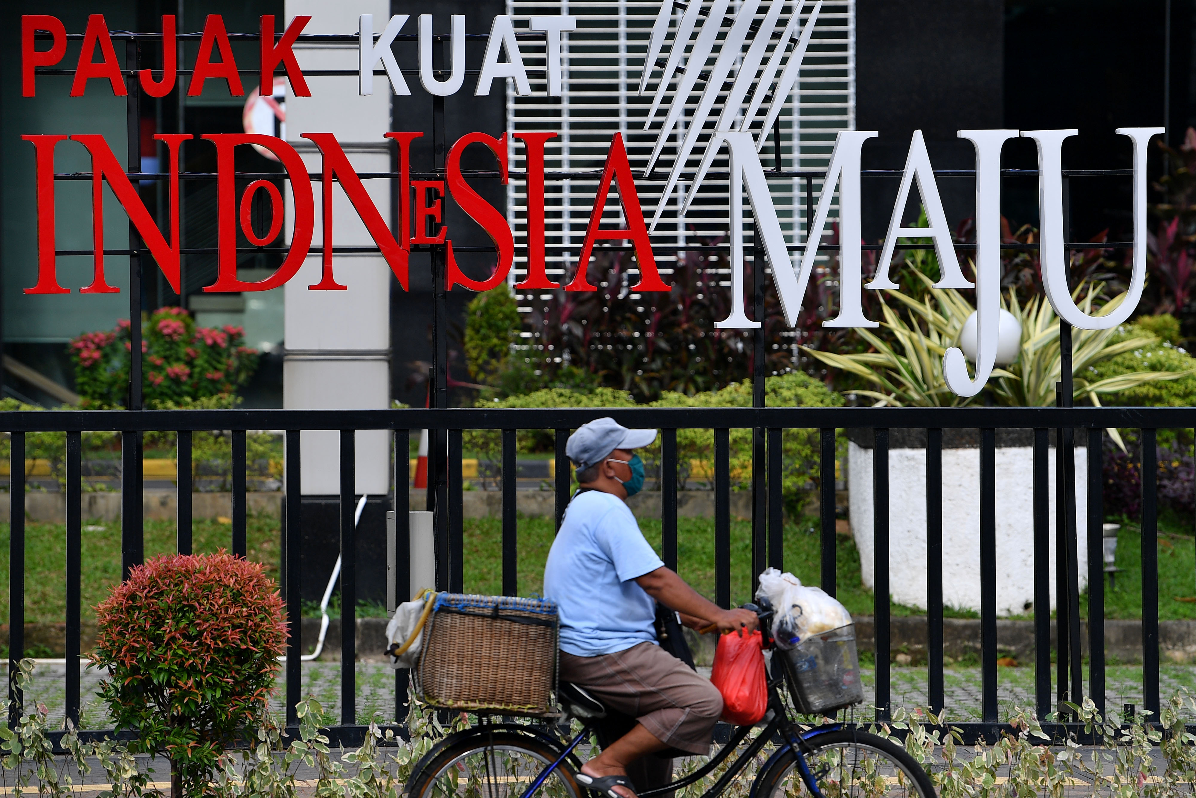 Pesepeda melintas did epan tulisan Pajak Kuat Indonesia Maju