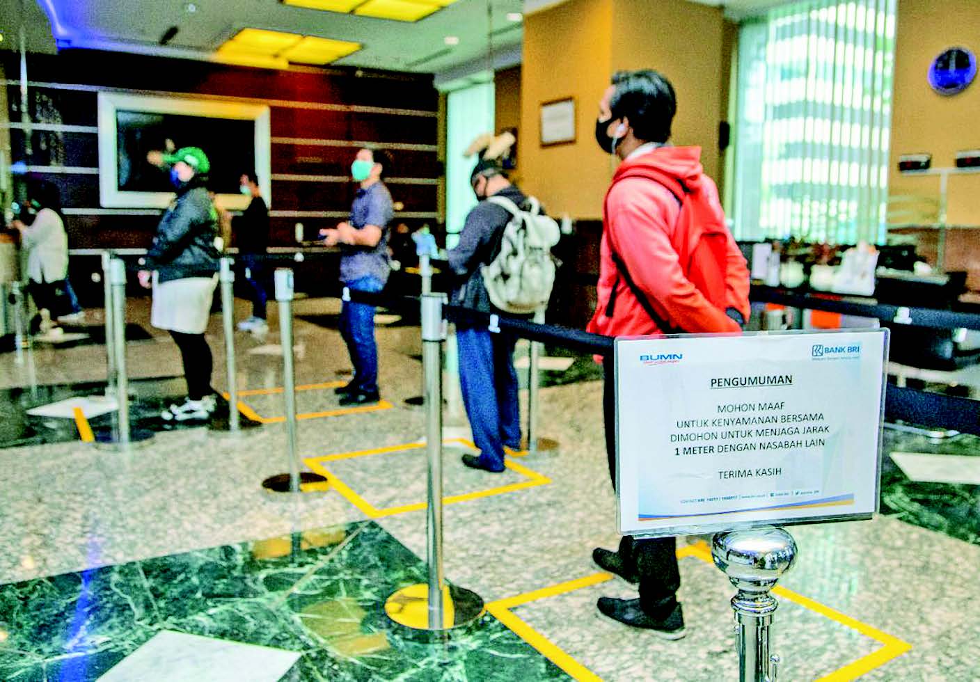 Pengumuman penerapan protokol kesehatan dipasang di tempat pelayanan nasabah Bank BRI.