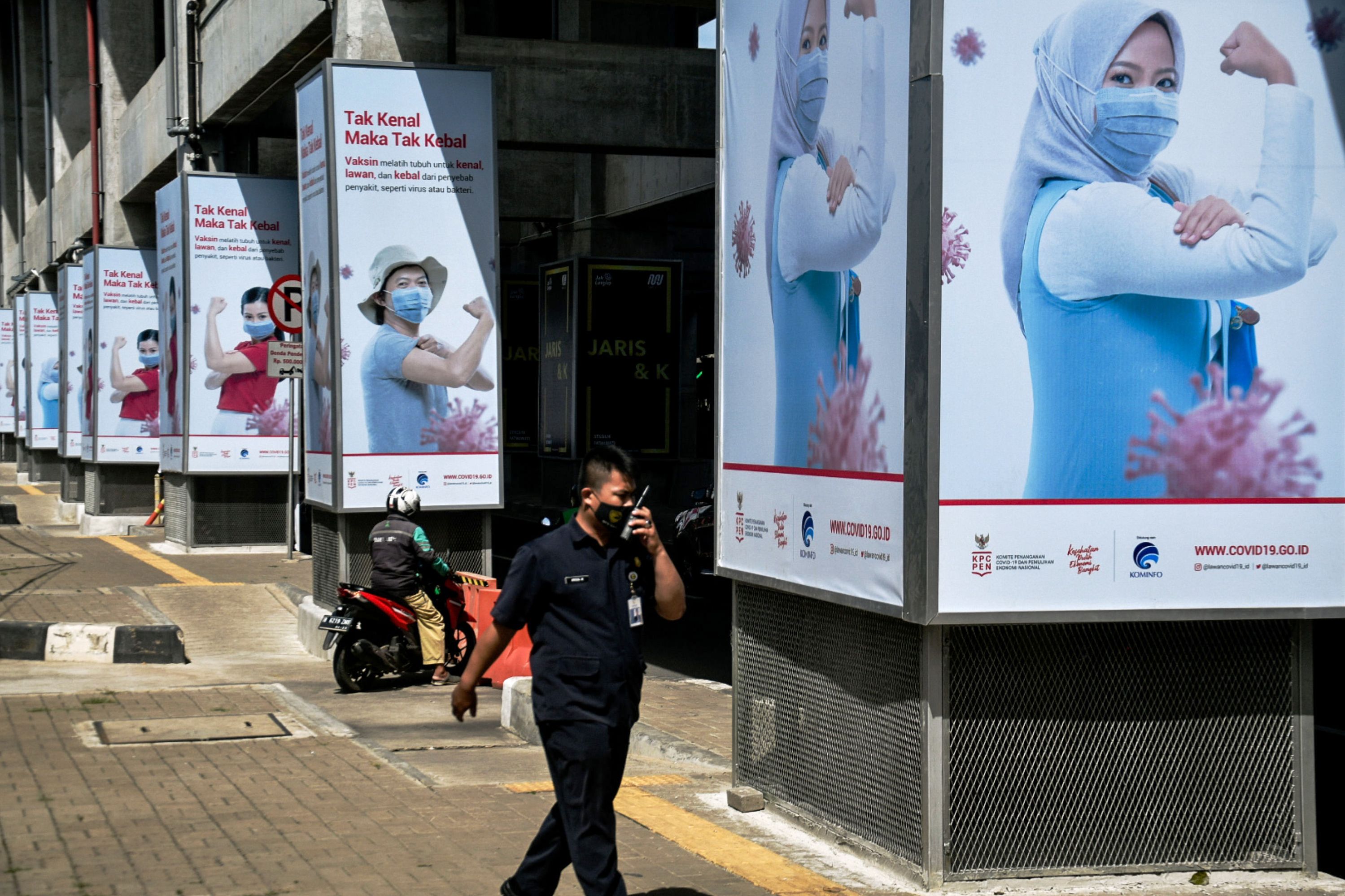 Seorang warga melewati iklan vaksin covid.