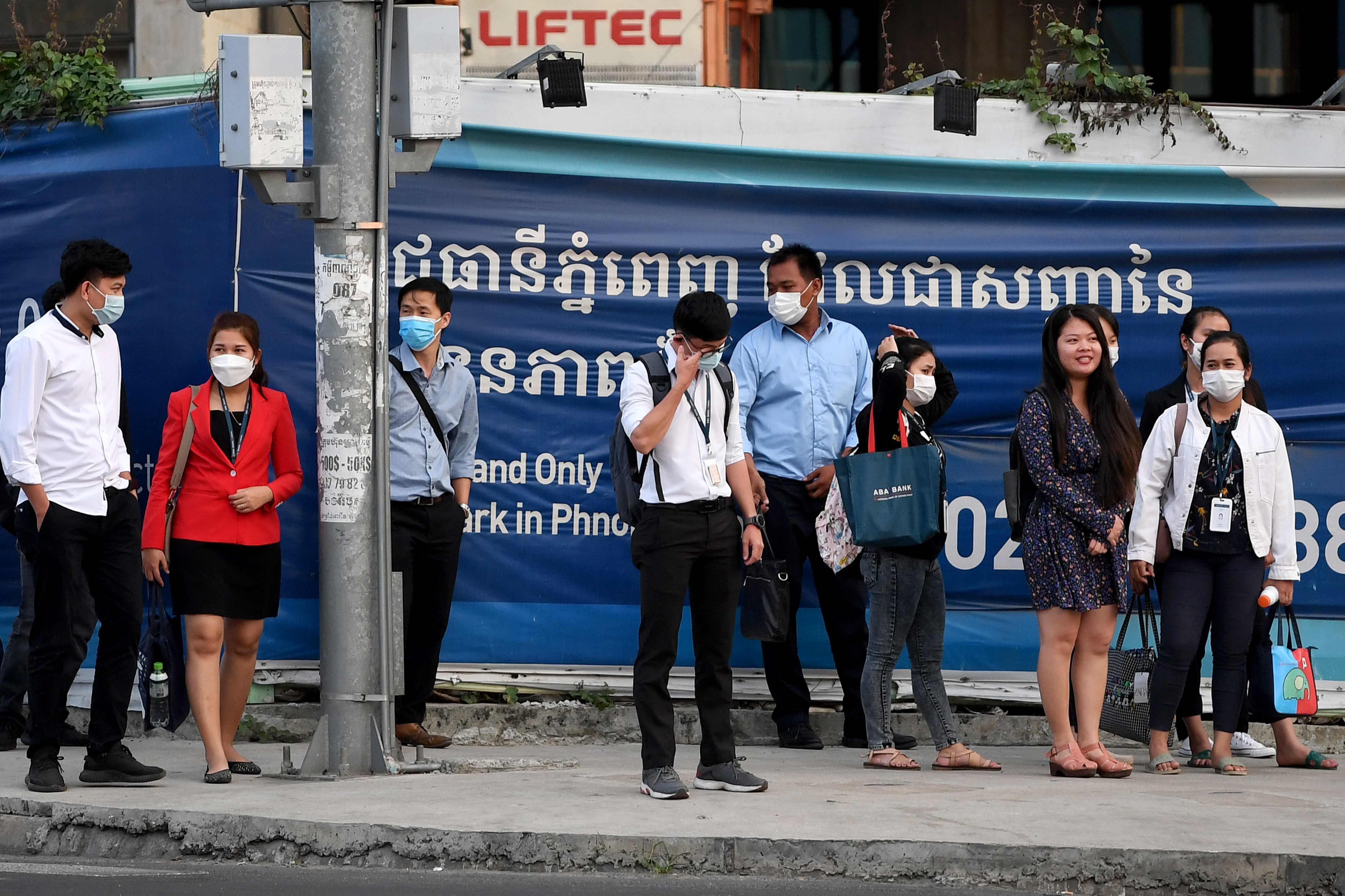 Orang-orang menunggu di lampu lalu lintas di jalan di Phnom Penh pada 11 Januari 2021.