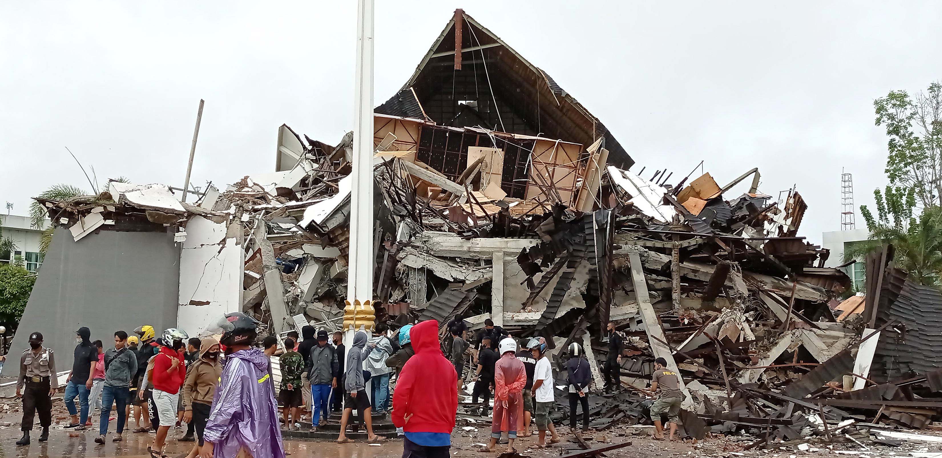 Warga mengamati Gedung Kantor Gubernur Sulawesi Barat yang rusak akibat gempa bumi, di Mamuju, Sulawesi Barat, Jumat (15/1).