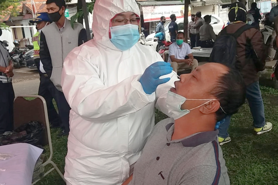 Petugas Dinkes Kota Cimahi melakukan rapid test antigen kepada pendatang yang keluar pintu tol Baros, Kamis (21/1/2021).