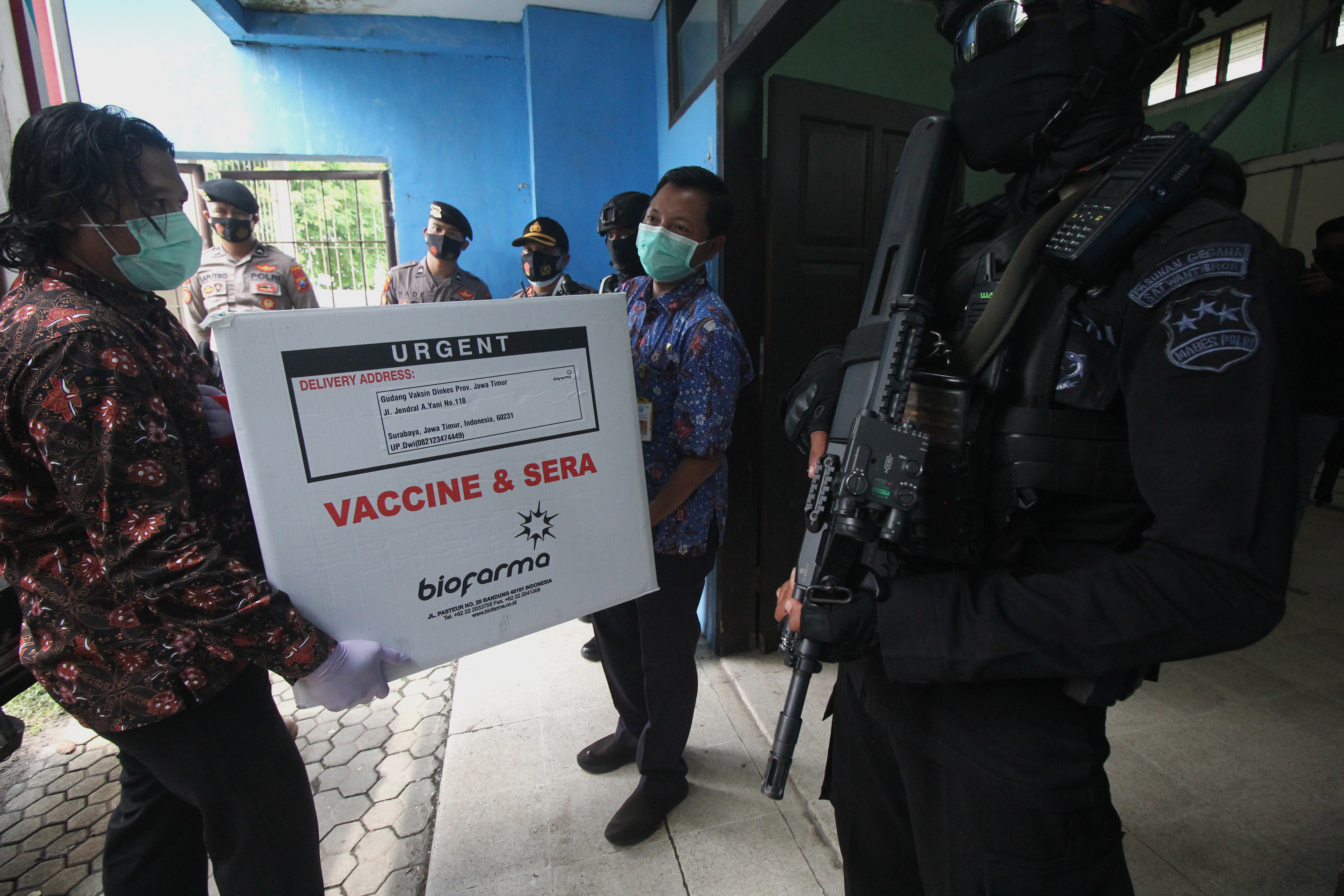  Personel Brimob berjaga saat proses bongkar muatan truk yang mengangkut vaksin COVID-19 Sinovac di kantor Dinkes Provinsi Jatim.
