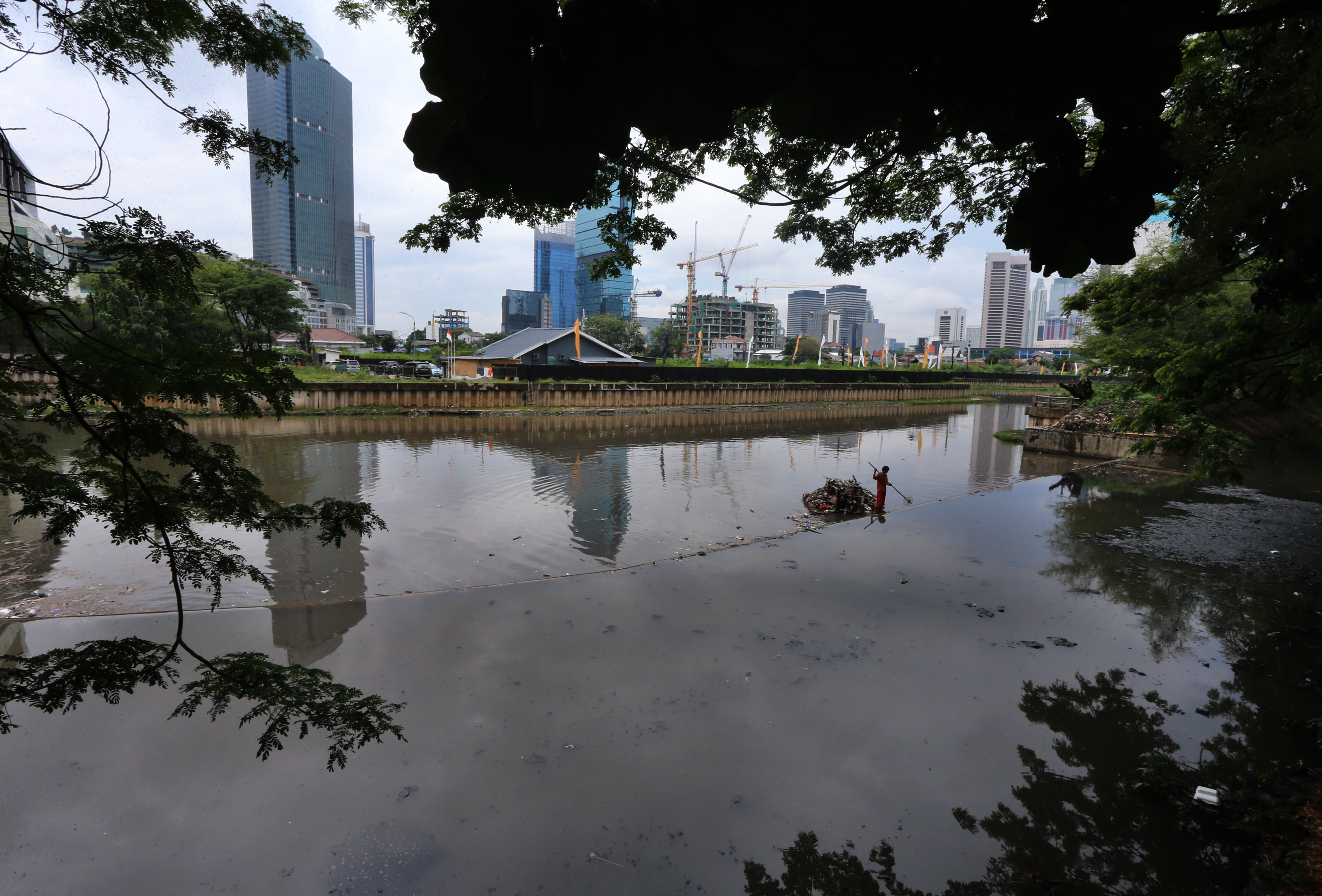 Seorang pekerja dari Dinas Pekerjaan Umum DKI Jakarta membersihkan sampah di Waduk Melati, Jakarta.