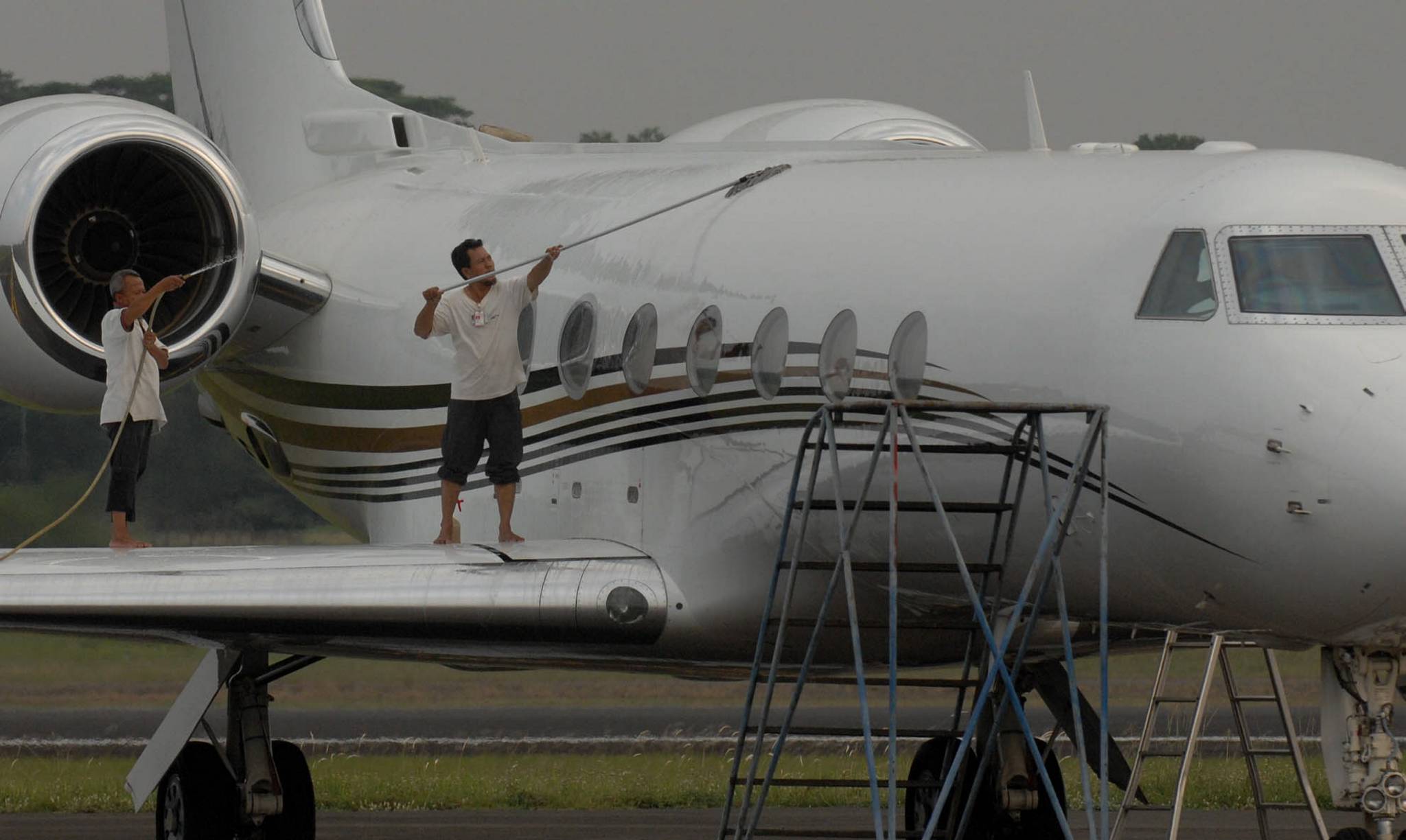  Dua pekerja melakukan perawatan bagian luar sebuah pesawat jet pribadi yang di parkir di Bandara Halim PK, Jakarta.